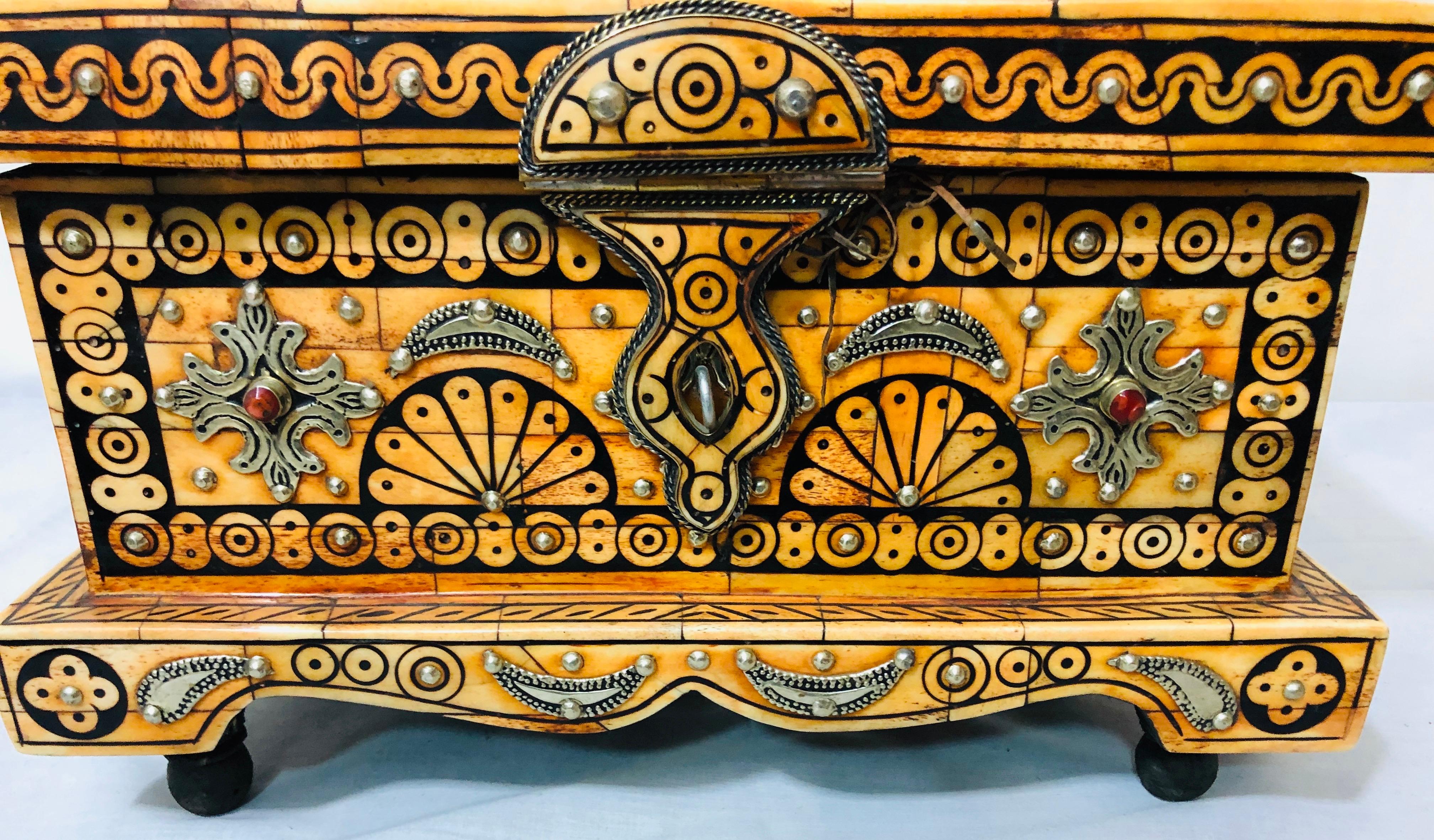 A decorative handmade orange bone and black tribal design chest or jewelry box. The chest interior is leather and features gorgeous brass inlay design with natural decorative stones.