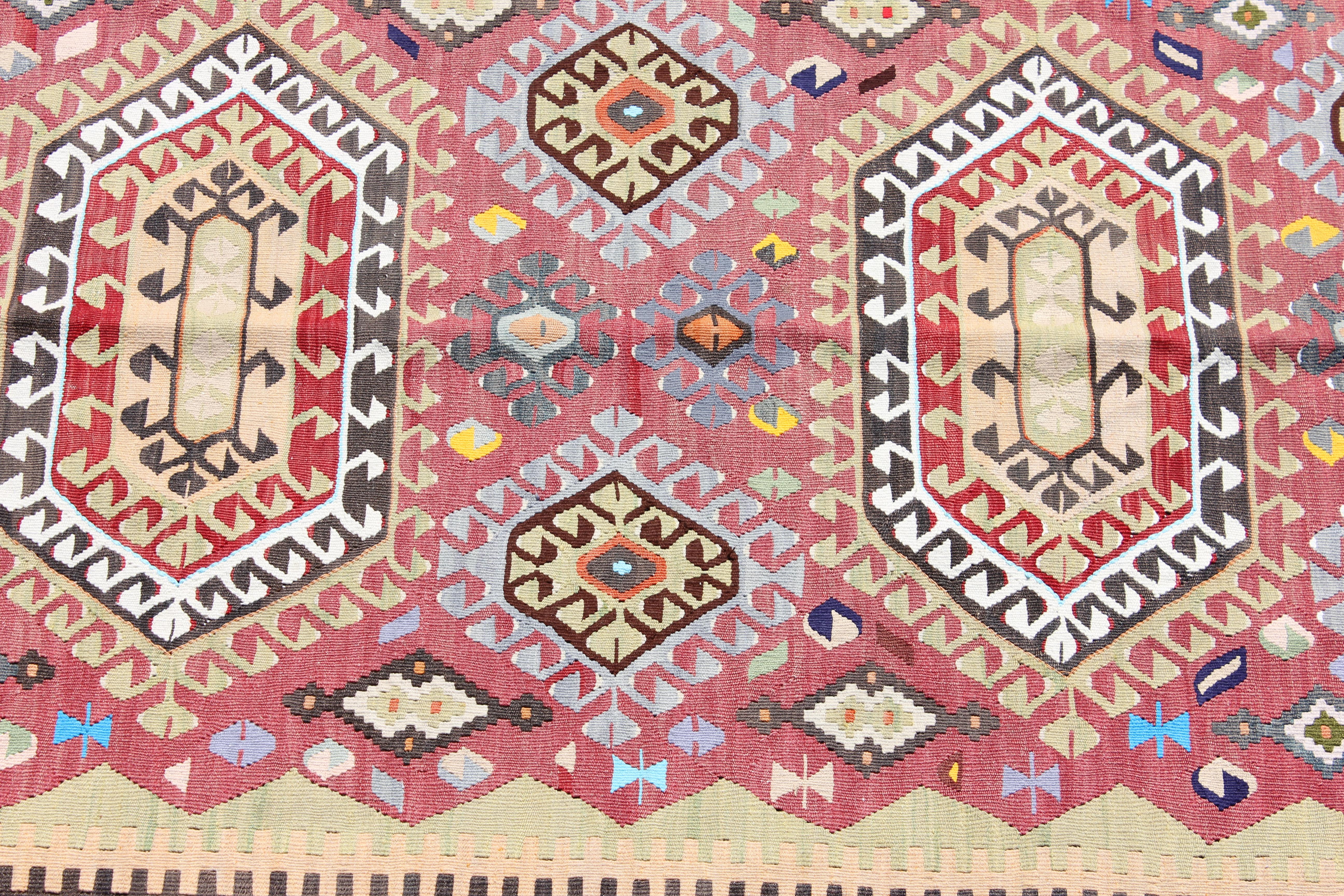 Wool and cotton handwoven tribal style Turkish Kilim. The rug has orange, blue, and red tones. It is from the Denizli region and is about 35 years old.