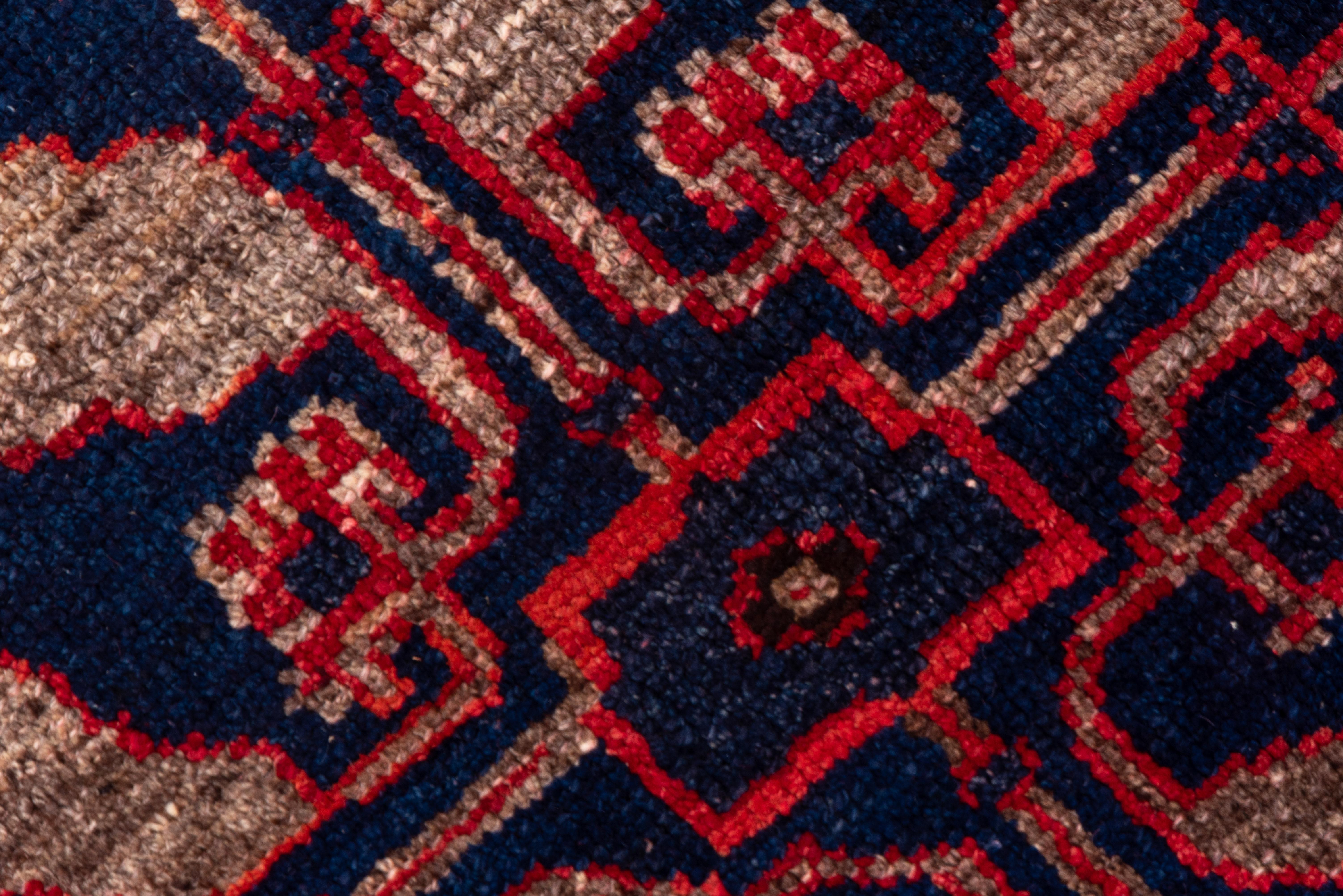 The spot worn, abrashed plain red field of this eastern Turkish piece features a pole medallion of three bold light grey and royal blue diamonds, all framed by a light grey border with a square Meander embracing fat crosses, rosettes and fringed