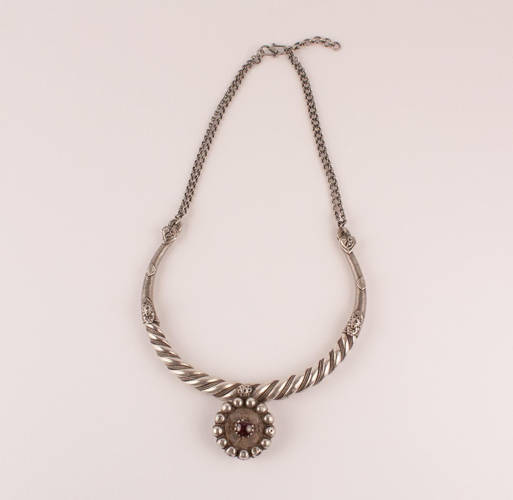 Authentic tribal Indian silver torque necklace from Rajasthan, India, circa 1950. The neckpiece is in perfect original condition and features beautiful silver hand work, a center pendant with traditional  glass bead replaced with a cabochon garnet,