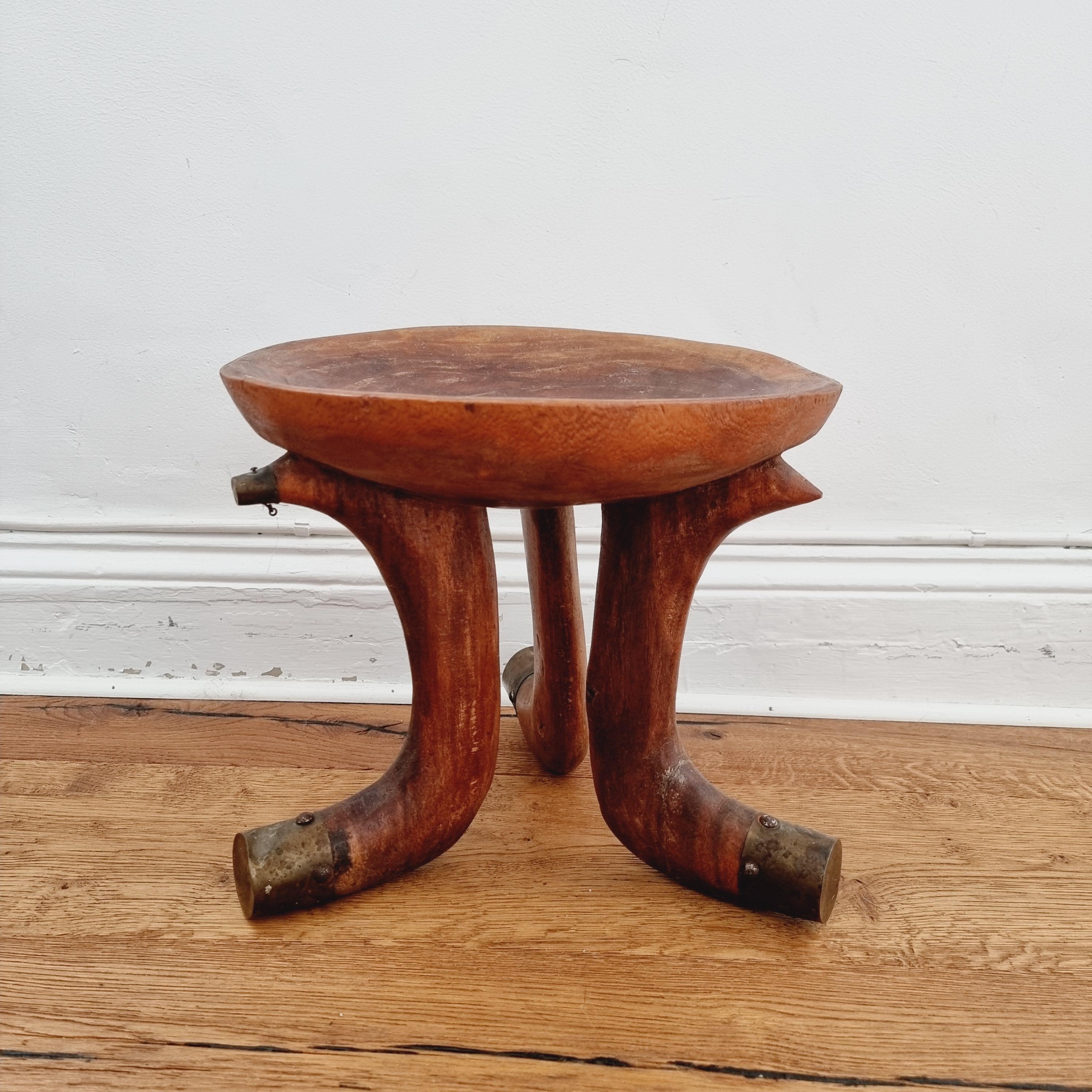 Tabouret tribal à trois pieds du sud de l'Éthiopie. Bois rougeâtre clair, les pieds sont partiellement recouverts de laiton. Début des années 1900 / première moitié du 20e siècle.

Provenance : P. Strand
Carl Braunerhielm 1925-2012 - employé du