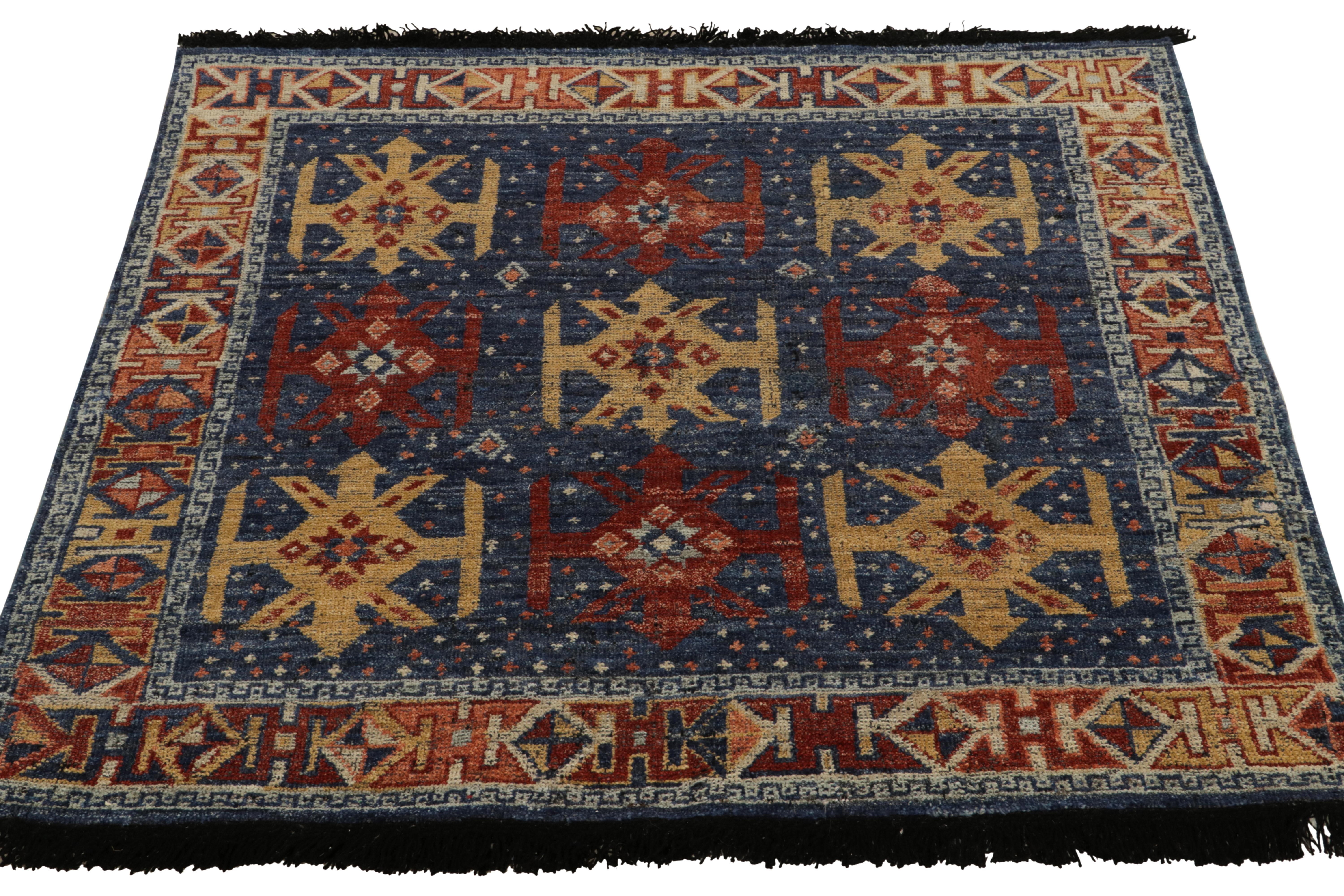 Dieser quadratische Stammesteppich aus der Burano-Kollektion von Rug & Kilim passt kaukasisches Stammesgefühl an moderne Qualität an und zeigt geometrische Muster in Rot und Ocker, die bequem auf sattem Blau sitzen und eine raffinierte Ästhetik der