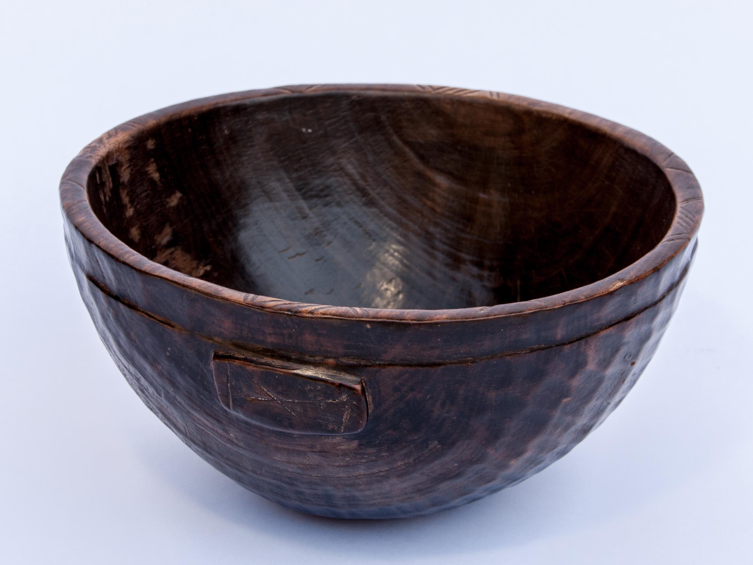 Tribal wooden bowl. Hand hewn, from Niger, mid-20th century. 11.5 inch diameter by 6 inches tall.
This rustic wooden bowl was fashioned by hand using very basic tools. It was used to hold food or grain. The dappled texture on the exterior, a result