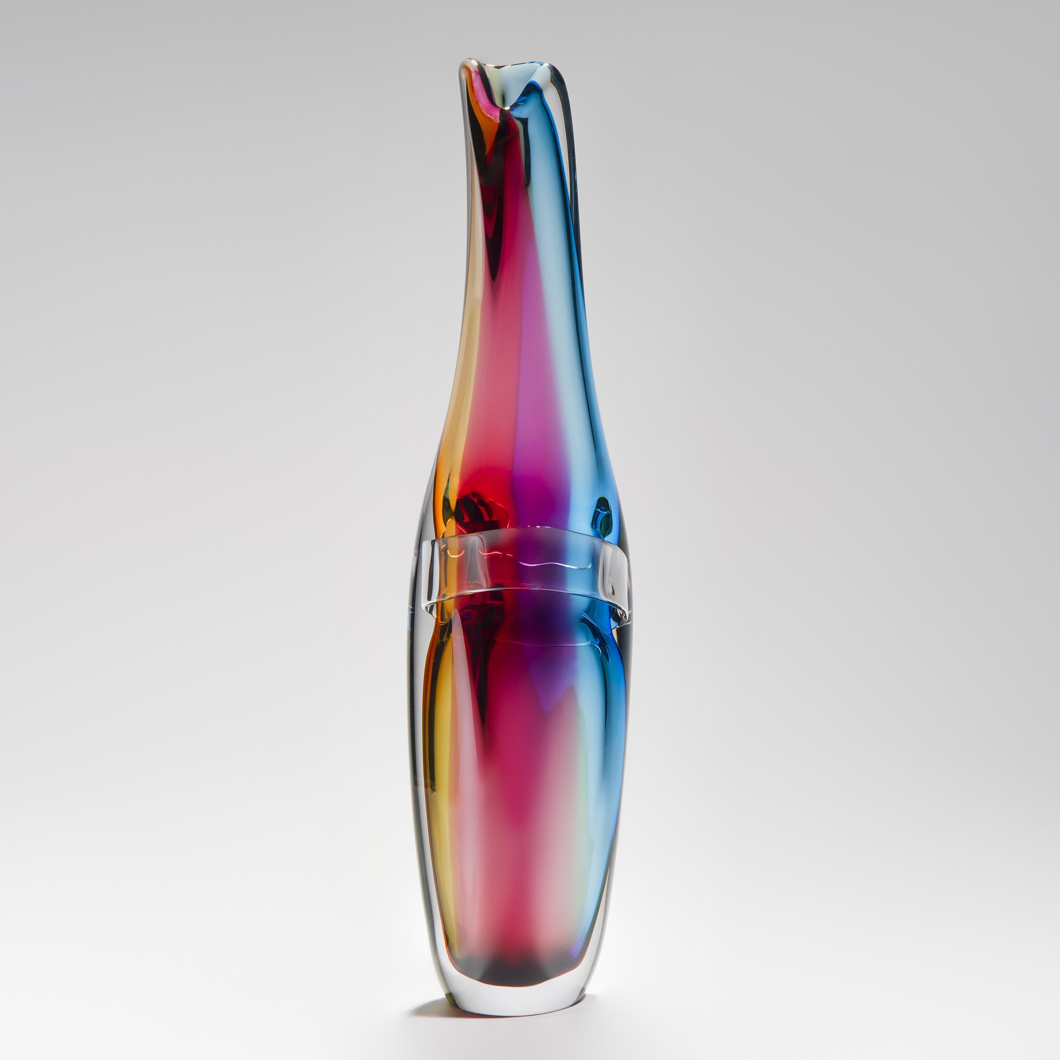 'Tricolarial 18' is a unique hand blown sculptural vase by the British artist Vic Bamforth. Blown in amber, red, purple and blue colored glass which are encased in clear glass to create this stunning piece. With soft, twisting lines, the form has