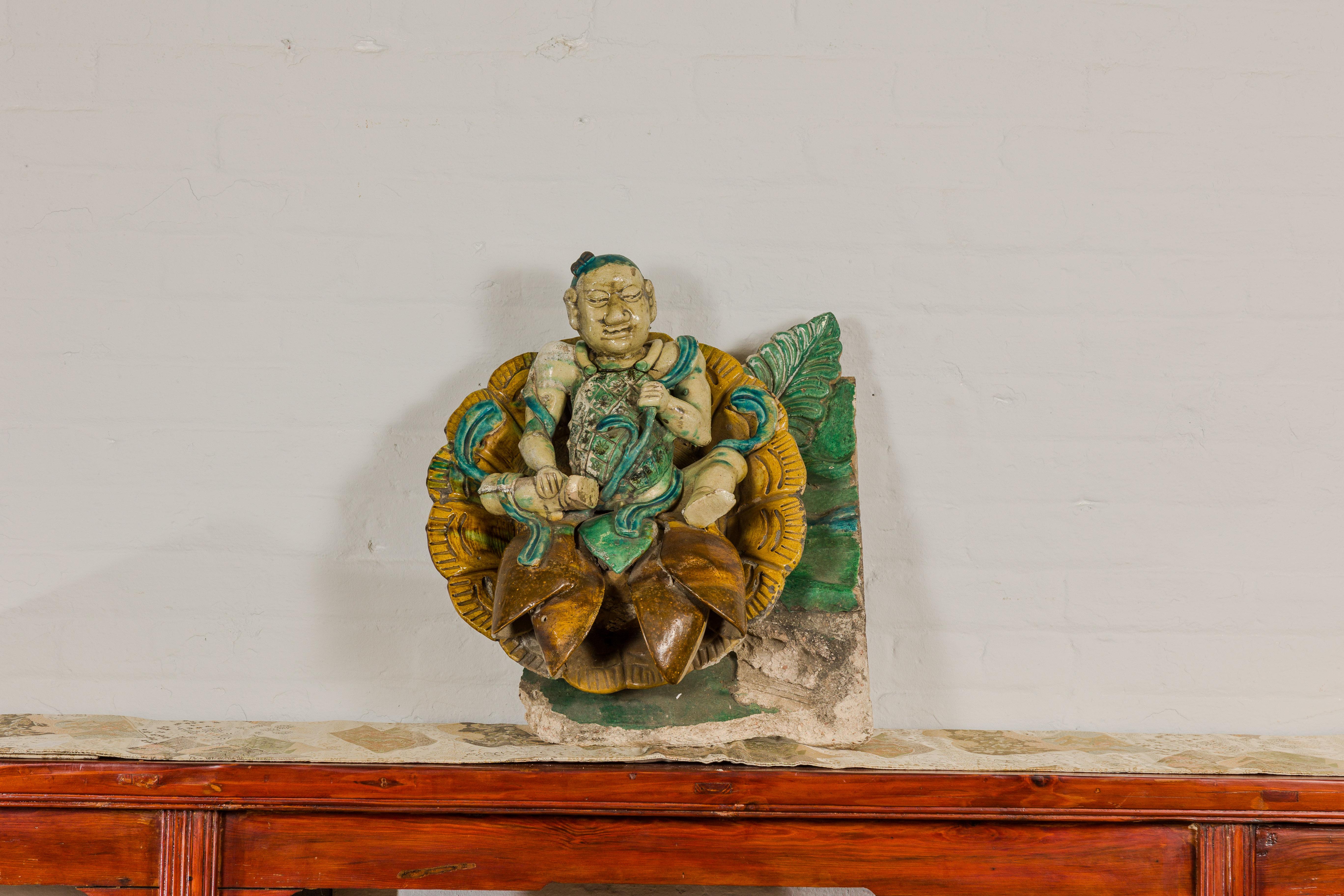 A Chinese Qing Dynasty period roof tile fragment from a temple, with tri-color green, turquoise and yellow color, and raised relief. This Chinese Qing Dynasty period roof tile fragment, originating from a temple, is a captivating piece of