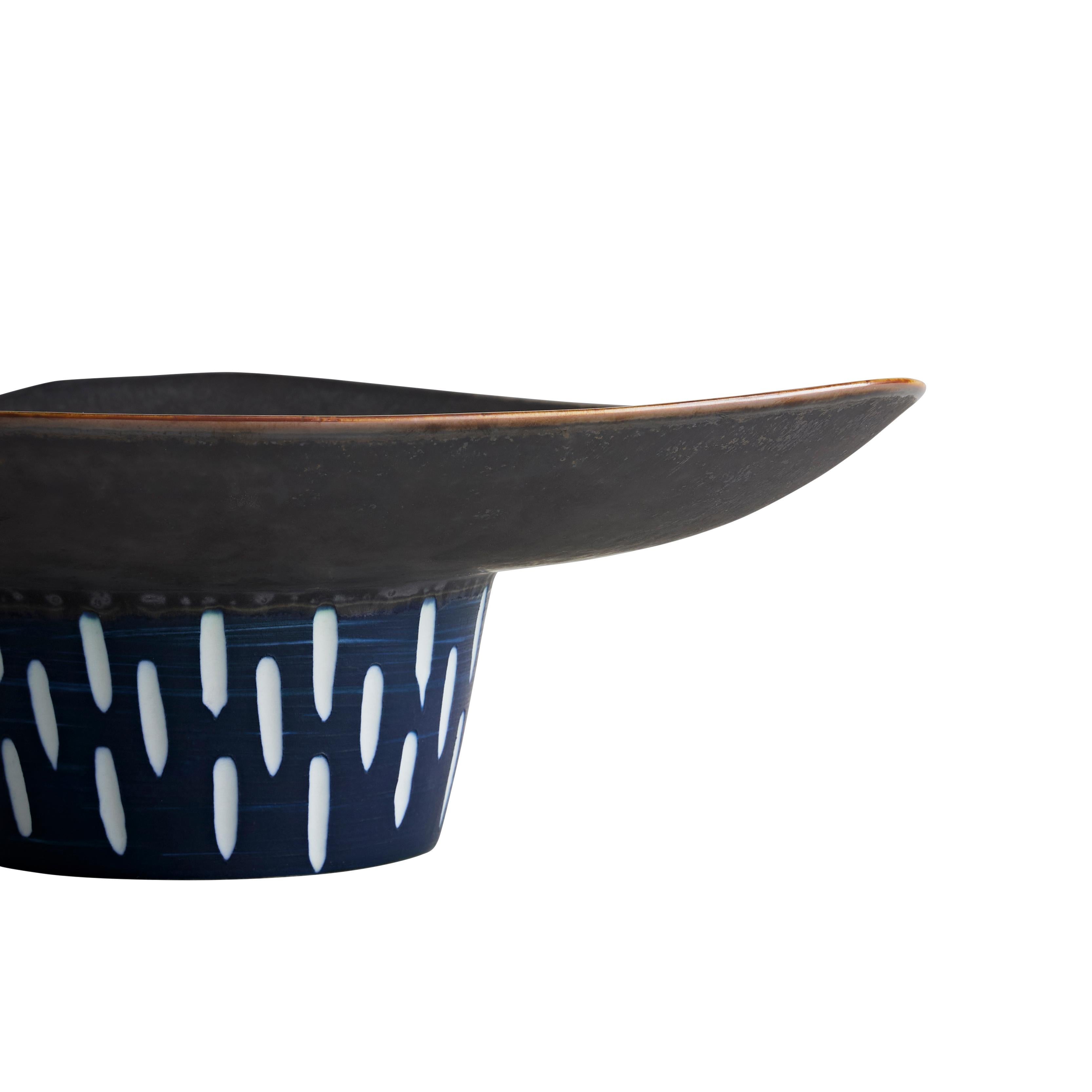 Une forme élégante en céramique de porcelaine, rehaussée d'un travail à la main de gouttes blanches texturées. La lèvre extérieure/le cadre est recouvert d'un glaçage réactif mat, dont le bord est souligné par un glaçage réactif brillant. Chaque