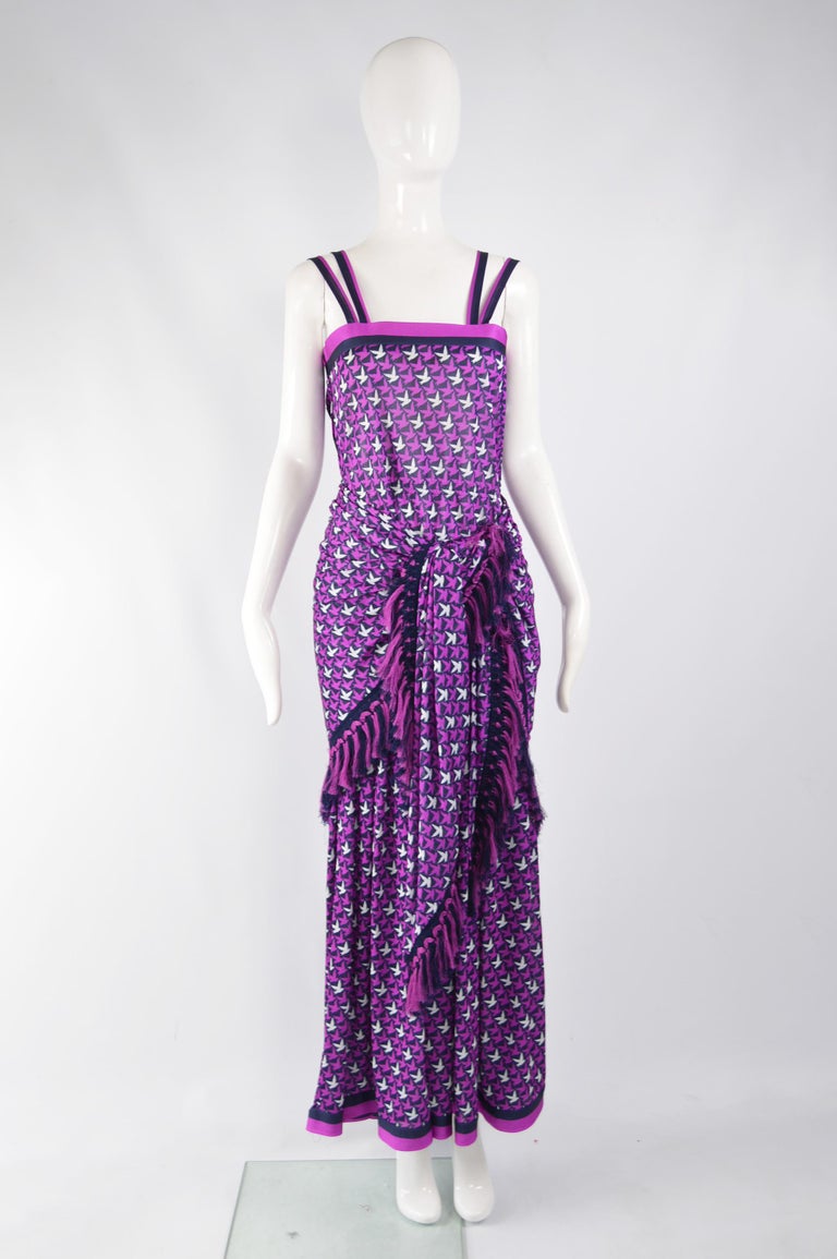 A fabulous vintage dress from the 70s by luxury French label, Tricosa. In a purple synthetic jersey with double straps and a bird print. It has a matching fringed scarf which can be worn over the shoulders or wrapped around the waist to give a more