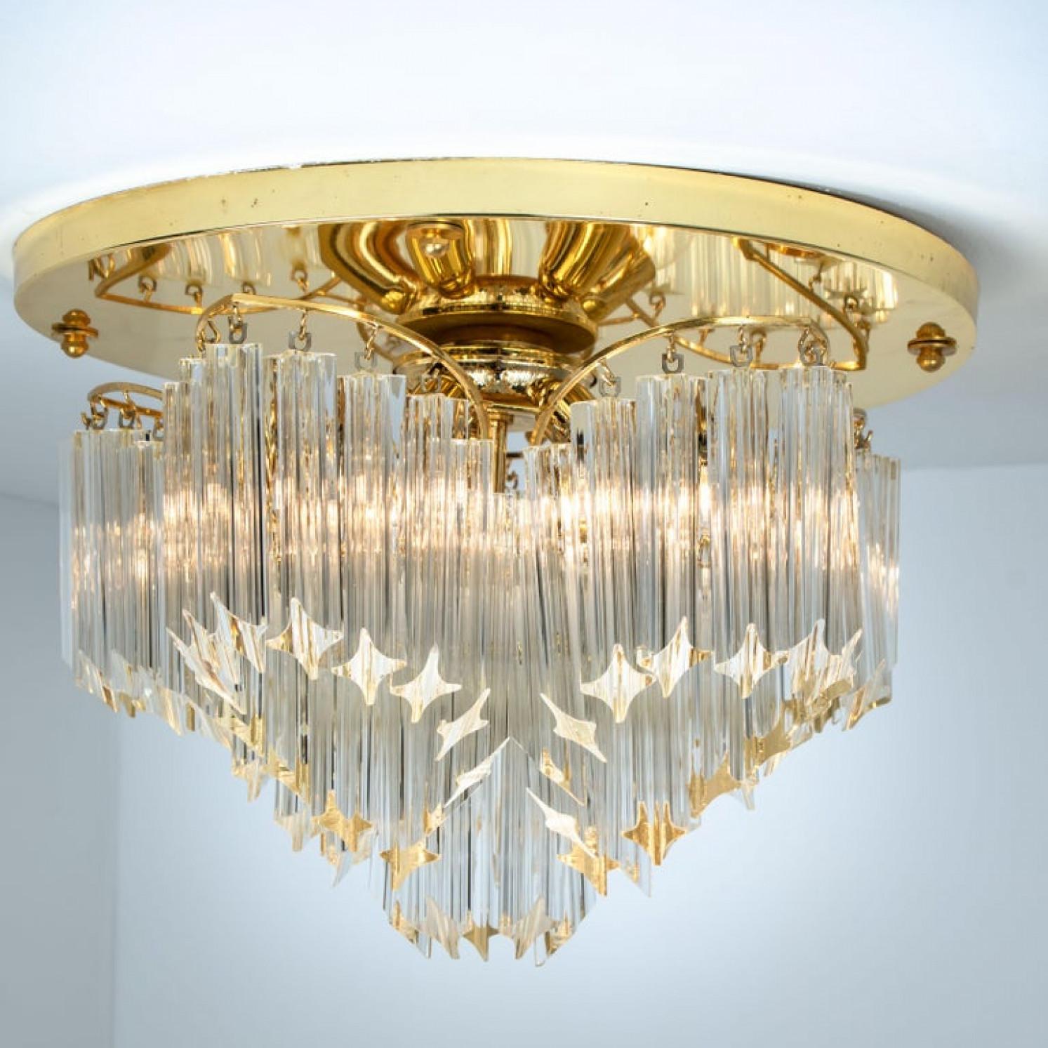 Questo eccezionale incasso è stato prodotto da Venini in Italia. La lampada è dotata di cristalli trasparenti di Murano Triedri di lunghezza variabile che creano un grande effetto di luce. I cristalli sono sospesi su una splendida cornice placcata