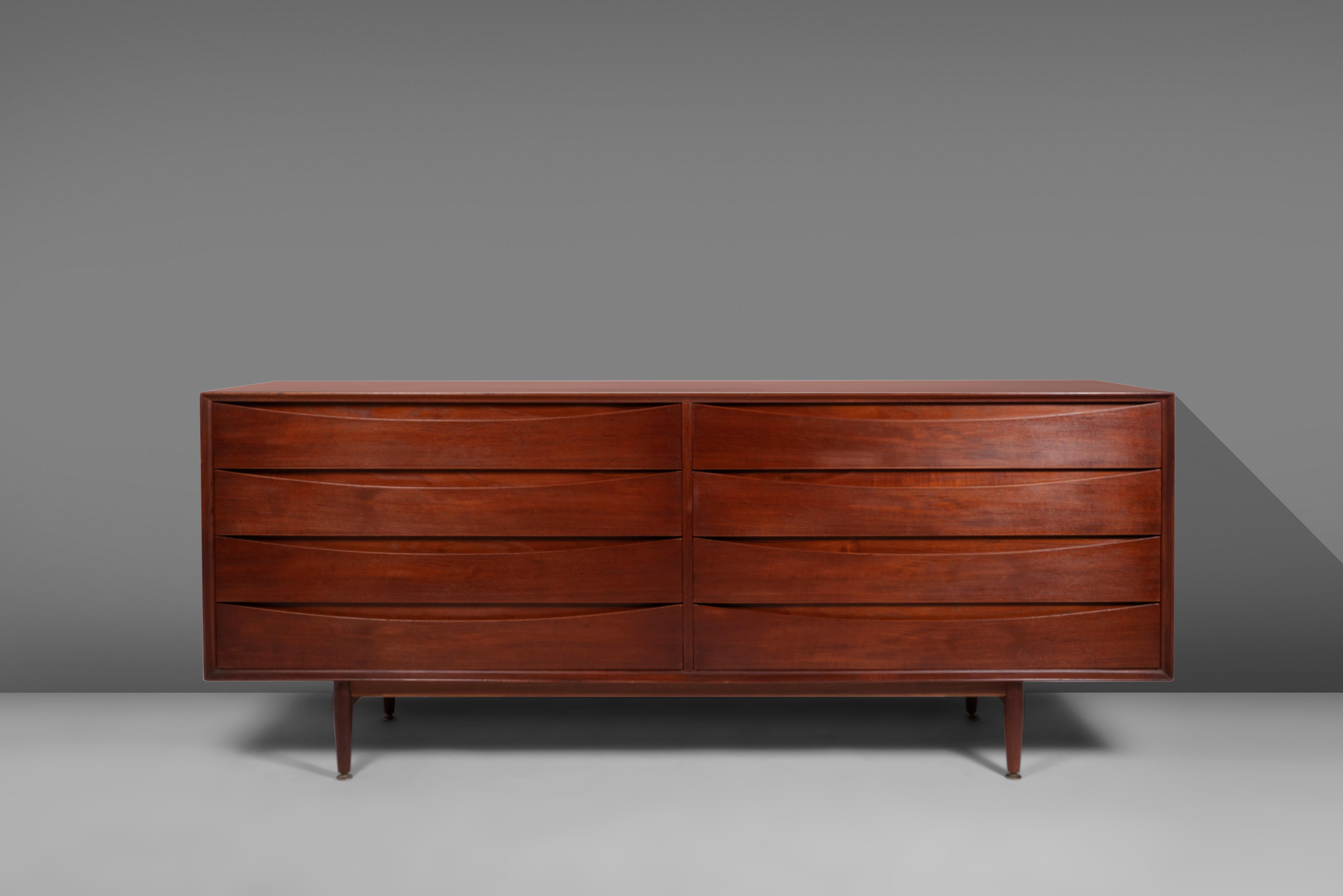 An iconic design by Arne Vodder, the mod. no. L-32-6 'Triennale' cabinet was produced by Sibast Mobler, c. 1950. Constructed in teak, the long eight drawer dresser which doubles as a credenza. The drawer faces are both architectural and functional