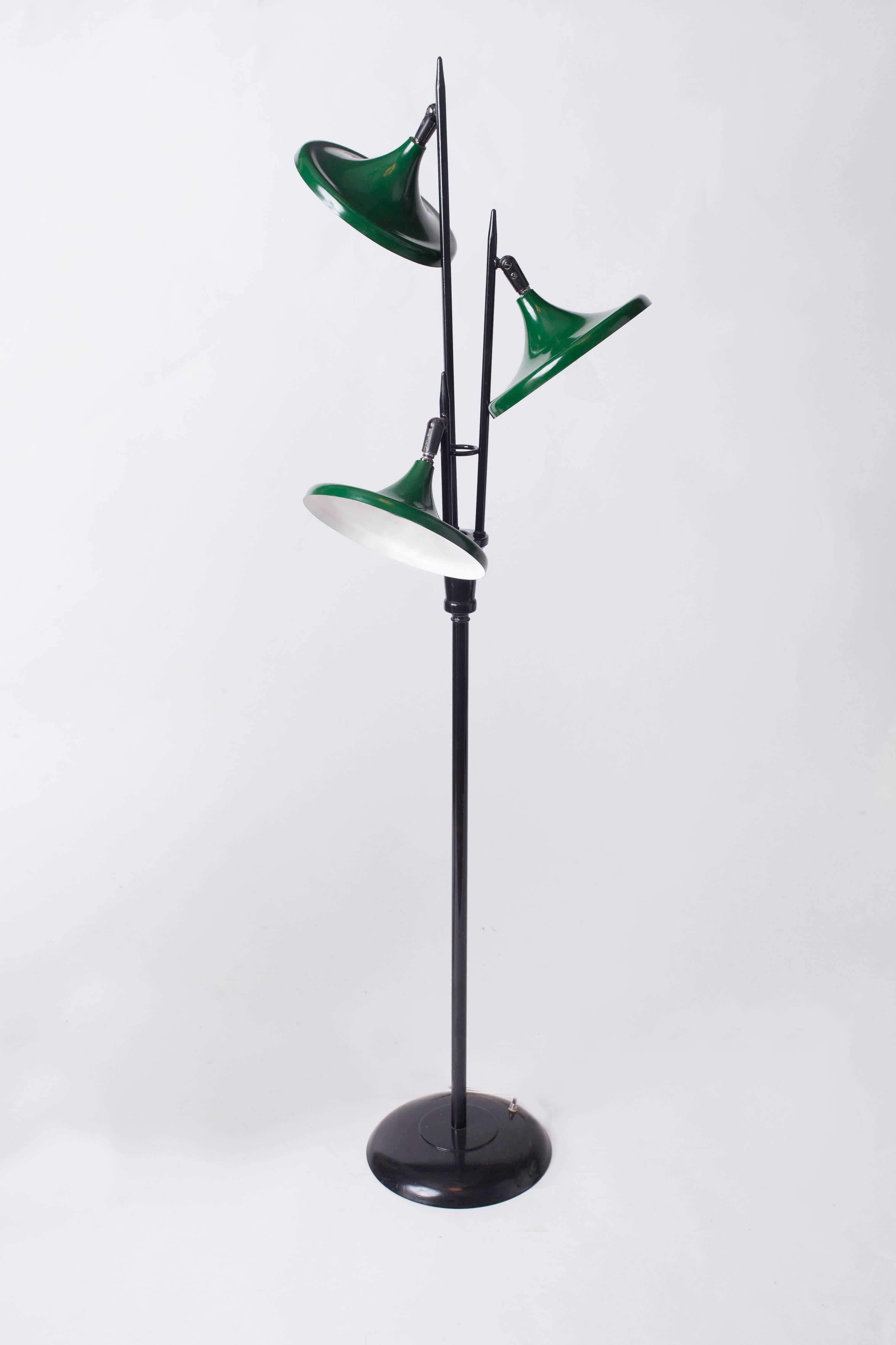 A harmonious and sleek midcentury three-light floor lamp in lacquered metal by Gerald Thurston for Lightolier. With adjustable dark green bell-shaped shades, a black lacquered base, and angled tapering shafts. United States, 1950's.