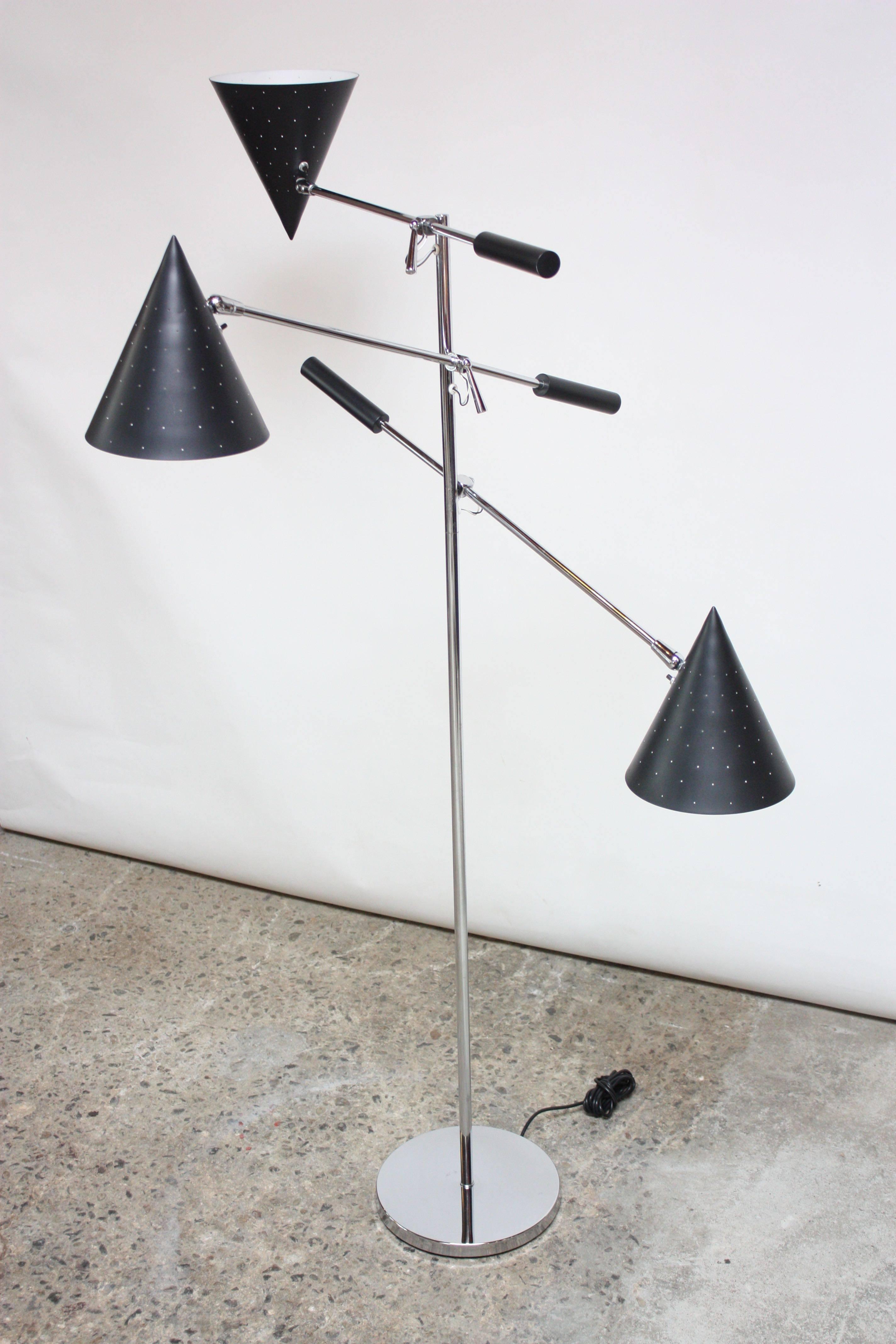 Striking three-fixture floor lamp manufactured by Lightolier in the 1950s. Composed of three conical, perforated shades in black mounted to chrome arms with counter weights which attach to a chromed stem and round base. Shades and arms offer