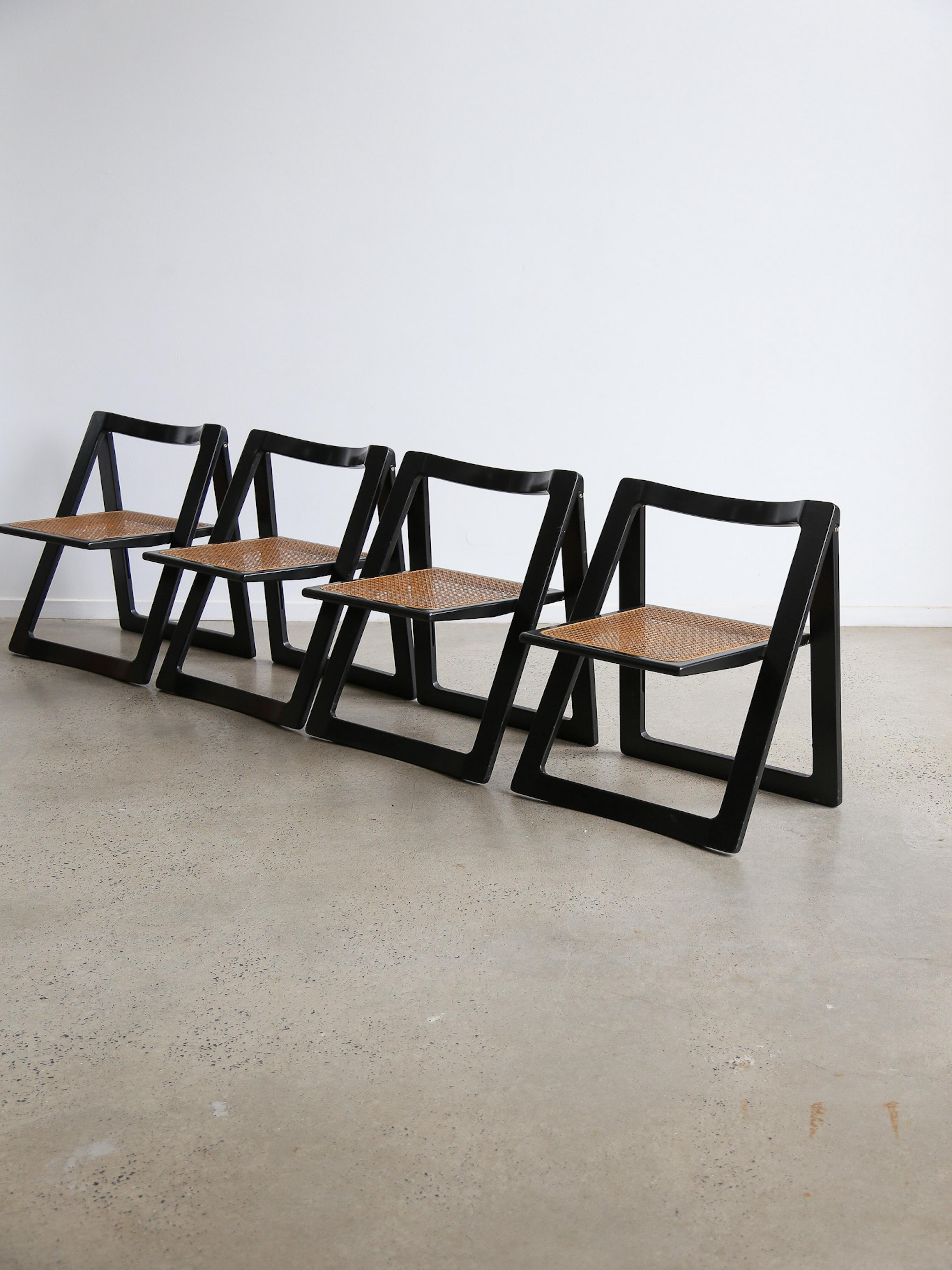 This set of four vintage folding chairs, designed by Aldo Jacober for Alberto Bazzini in the 1960s, showcases the elegance of Italian mid-century modern design. Each chair features a sturdy beech wood and black lacquer finish.

The seats are made of