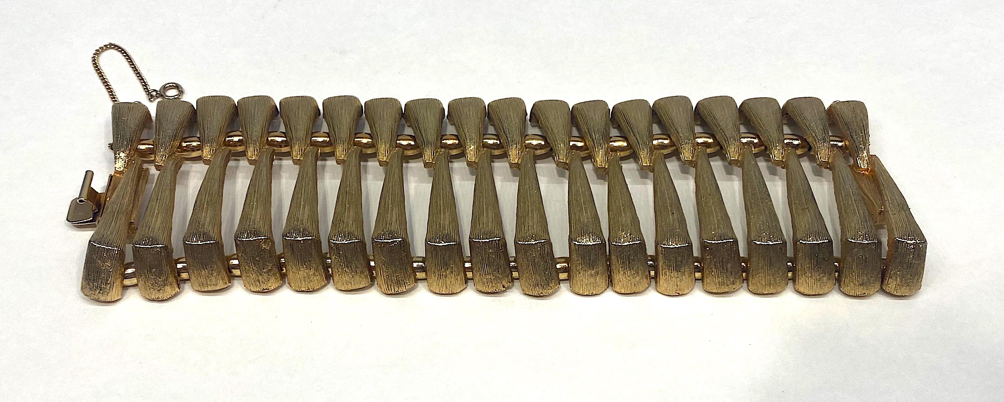 A rare wide Trifari mid to late 1950s bracelet in a textured satin gold plate. The design is three dimensional and abstract in the use of eighteen 2.13 inch wide links. The links are cast with the illusion of two separate triangular pieces facing