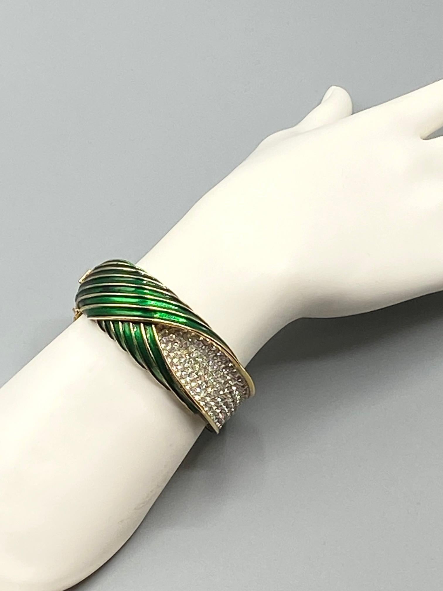 A very uniquely designed bangle style bracelet by Trifari from the 1960s. It is domed with swirling concave stripes cast into the upper and lower metal parts. The stripes are green enamel with the top edges left in gold as accent and contrast to the
