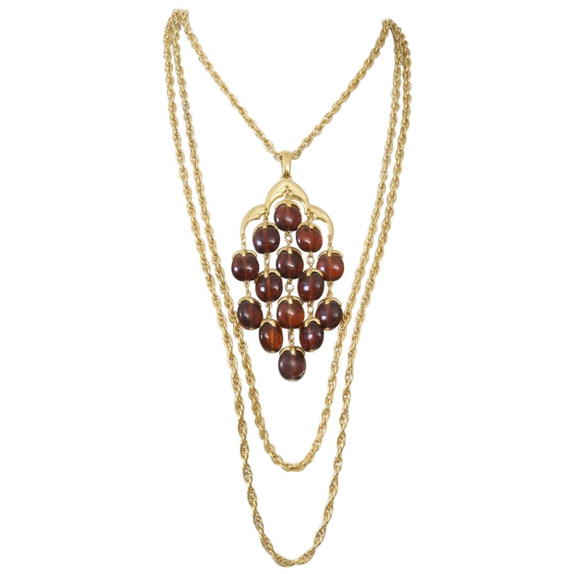 ca. 1960-70er Jahre Trifari Halskette und Ohrringe, die Halskette besteht aus drei Goldketten, die kürzeste davon mit einem großen Anhänger mit frei hängenden braunen durchscheinenden Steinen. Die dazu passenden Ohrringe in Form eines Kronleuchters