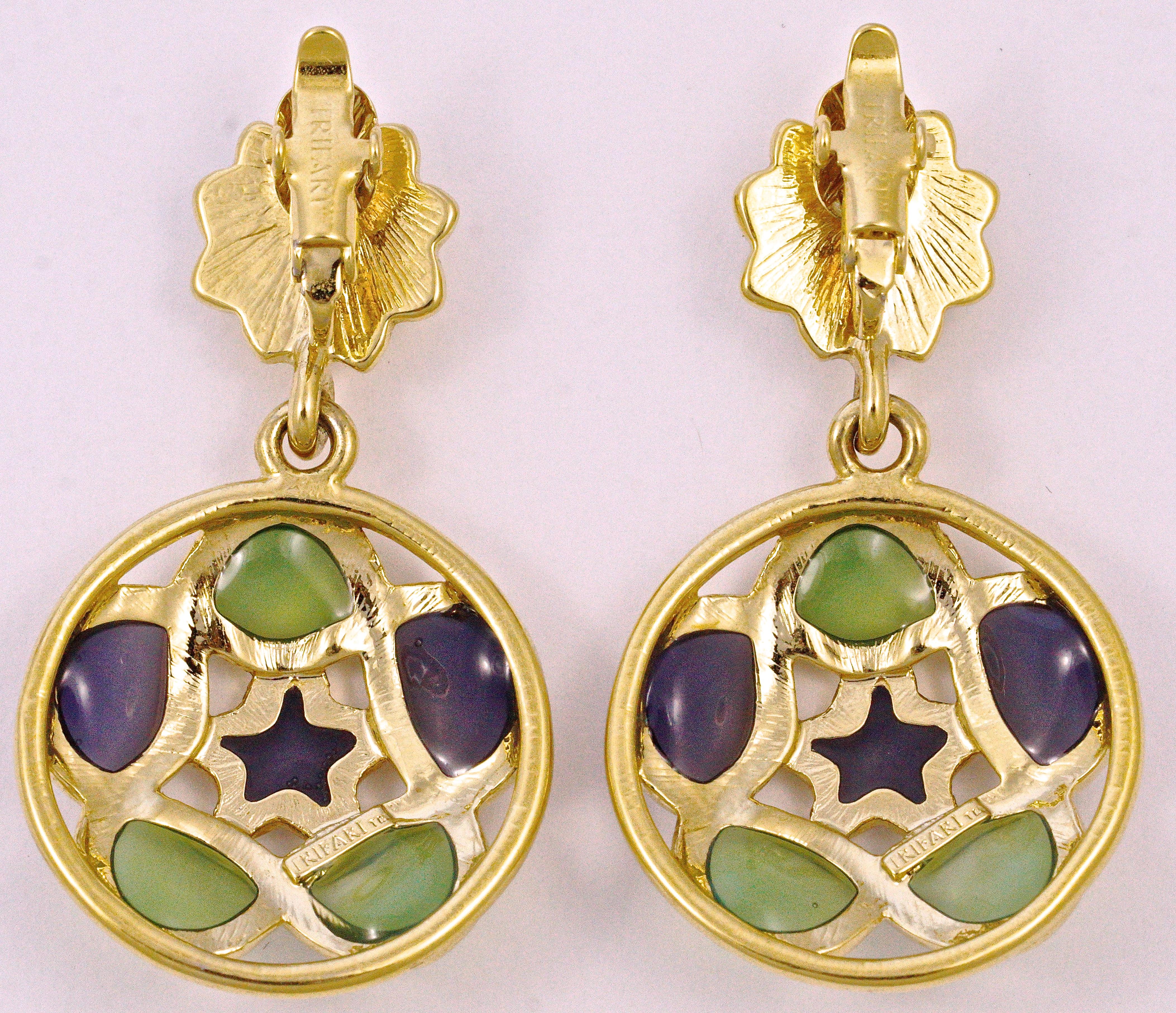 Lovely Trifari 1980s gold plated clip on earrings, featuring green and lilac glass surrounding a star, dropping from a sun face design top. Measuring diameter 2.8cm / 1.1 inches. 

These unusual quality vintage Trifari earrings are fun and