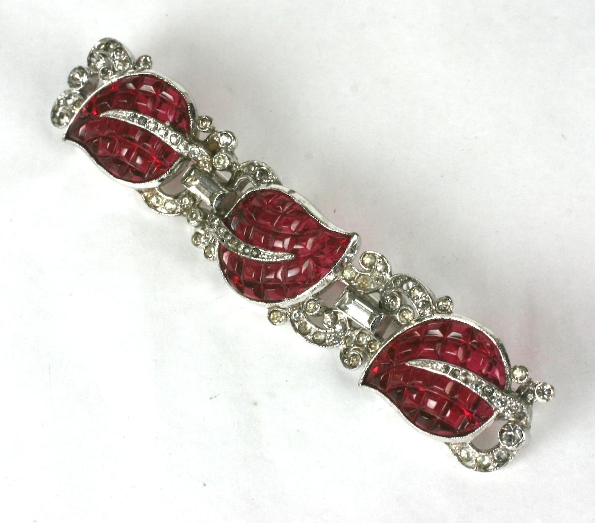 Trifari Alfred Philippe Invisibly set KTF ruby leaf art deco brooch. Bar form composed of three invisibly set glass leaves, crystal pave and baguettes set in rhodium plated base metal.
This brooch is characteristic of patented KTF pieces from the