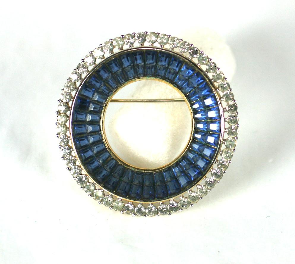 Trifari Alfred Philippe faux sapphire invisibly set circle brooch, set in gilt metal with a crystal rhinestone surround. Highly collectible Trifari series, with sapphire waffle glass, expertly imitating the invisibly set gem stone settings of Van