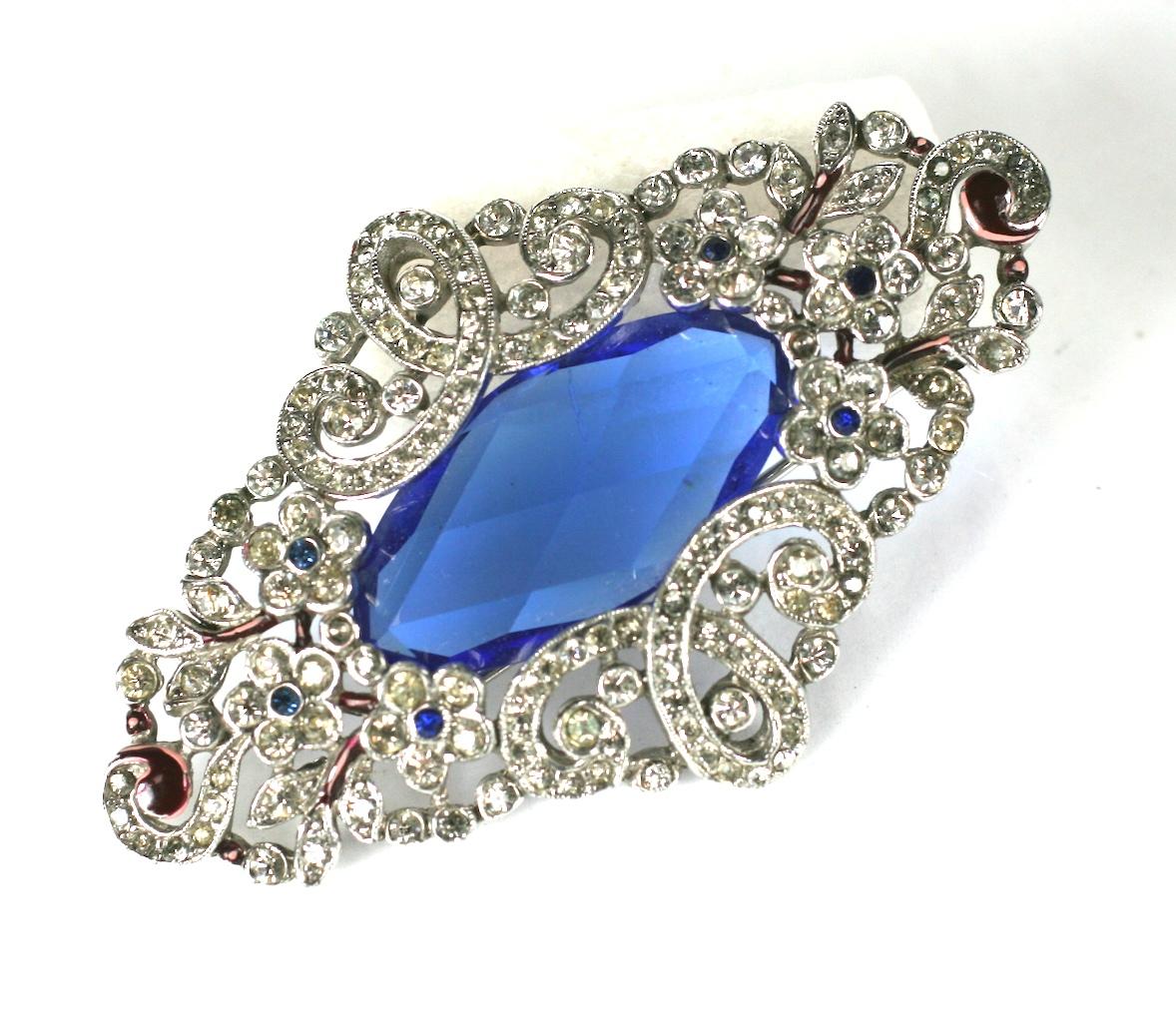 Trifari Alfred Phillipe Art Deco brooch with pave and enamel flowers and garlands surrounding a back set faceted blue stone. 
1930's USA.  2.75