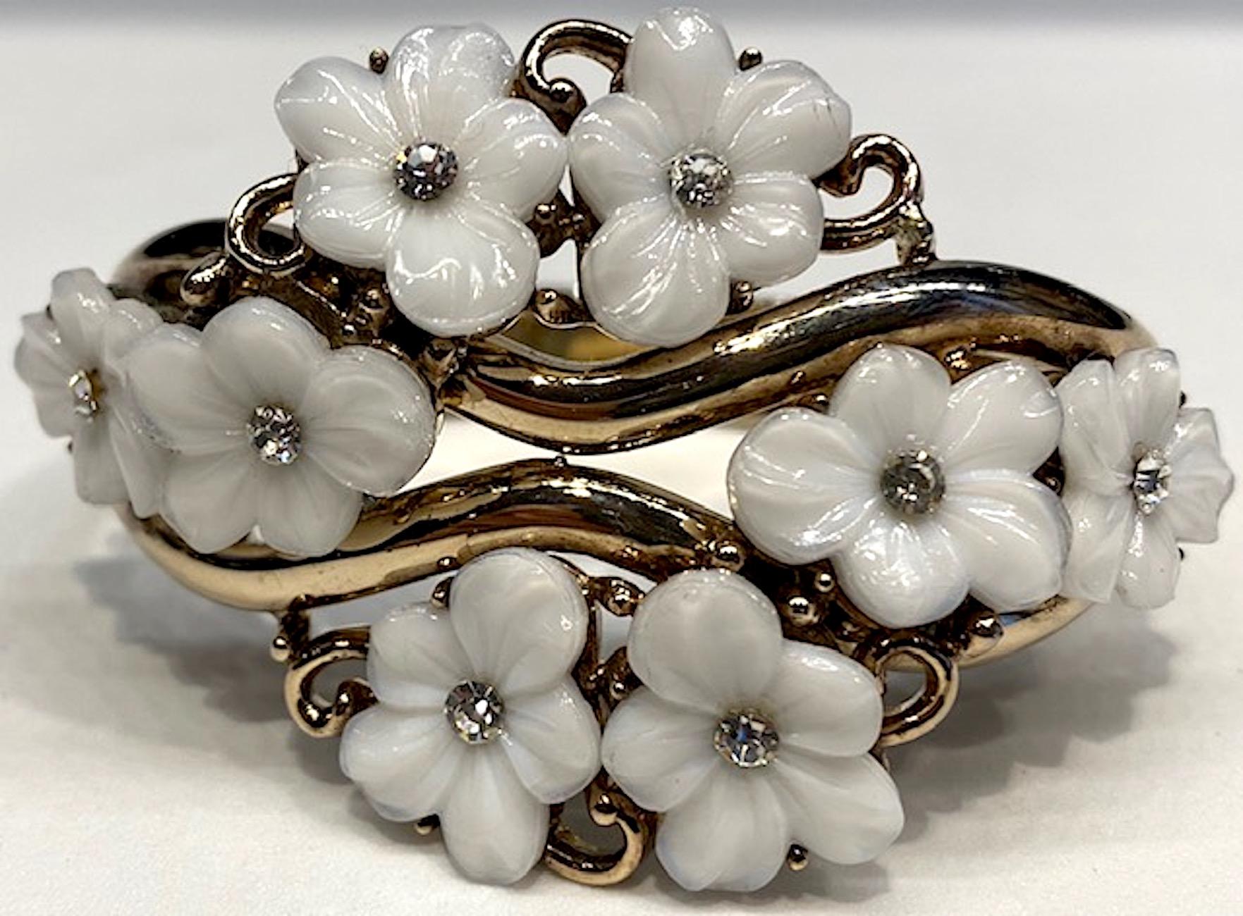 A beautifully constructed Trifari gold tone bangle with molded glass flowers with rhinestone accent by head designer Alfred Philippe. Patented design in 1951. Eight lovely white molded glass flowers are set into a rigid gold bangle with decorative