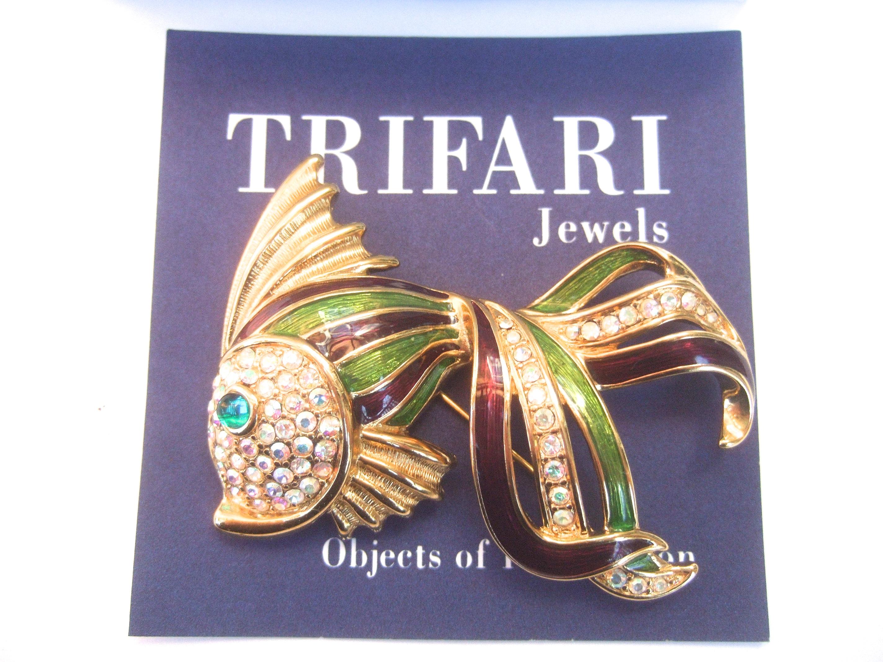 Trifari crystal enamel large scale fish brooch in Trifari box c 1997
The stylized gilt metal fish brooch is encrusted with a cluster
of Aurora Borealis crystals that distinguish the fish's face
The fish's eye is embellished with an emerald green
