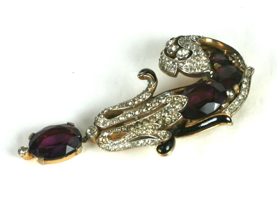 Collectible and rare Eugenie Series Plume Clip by Trifari, in gilt metal with black enamel and purple oval pastes. Large, extravagant Retro design is dimensional and striking. An amythest paste pendant drop dangles from the plume formed clip brooch.