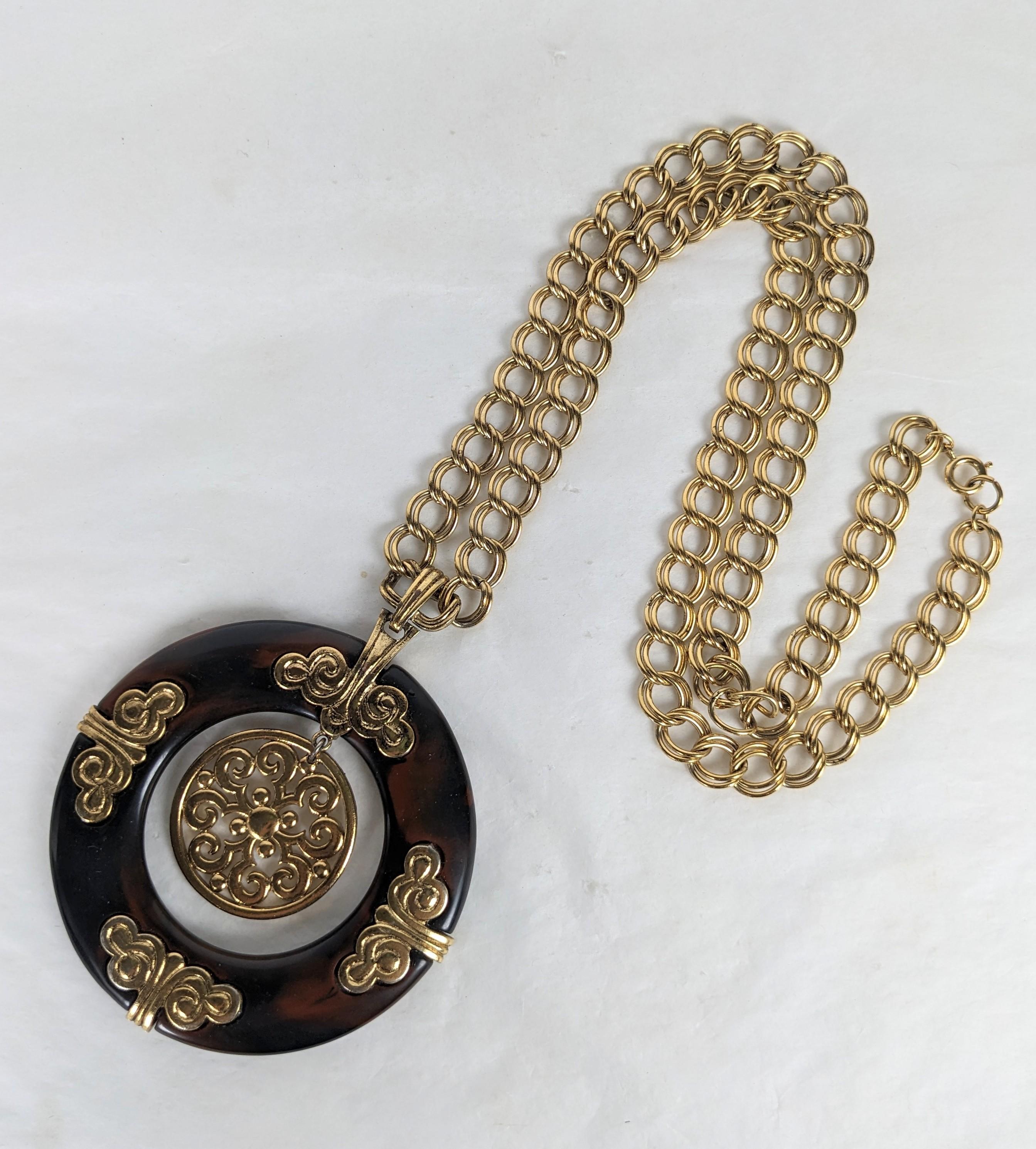 Llamativo y elegante Collar Colgante Trifari Faux Tortoise Mod con matices ligeramente asiáticos. Un gran anillo de baquelita hecho a imitación de una tortuga está engastado con motivos de nubes doradas y un motivo circular central dorado. Cadena de