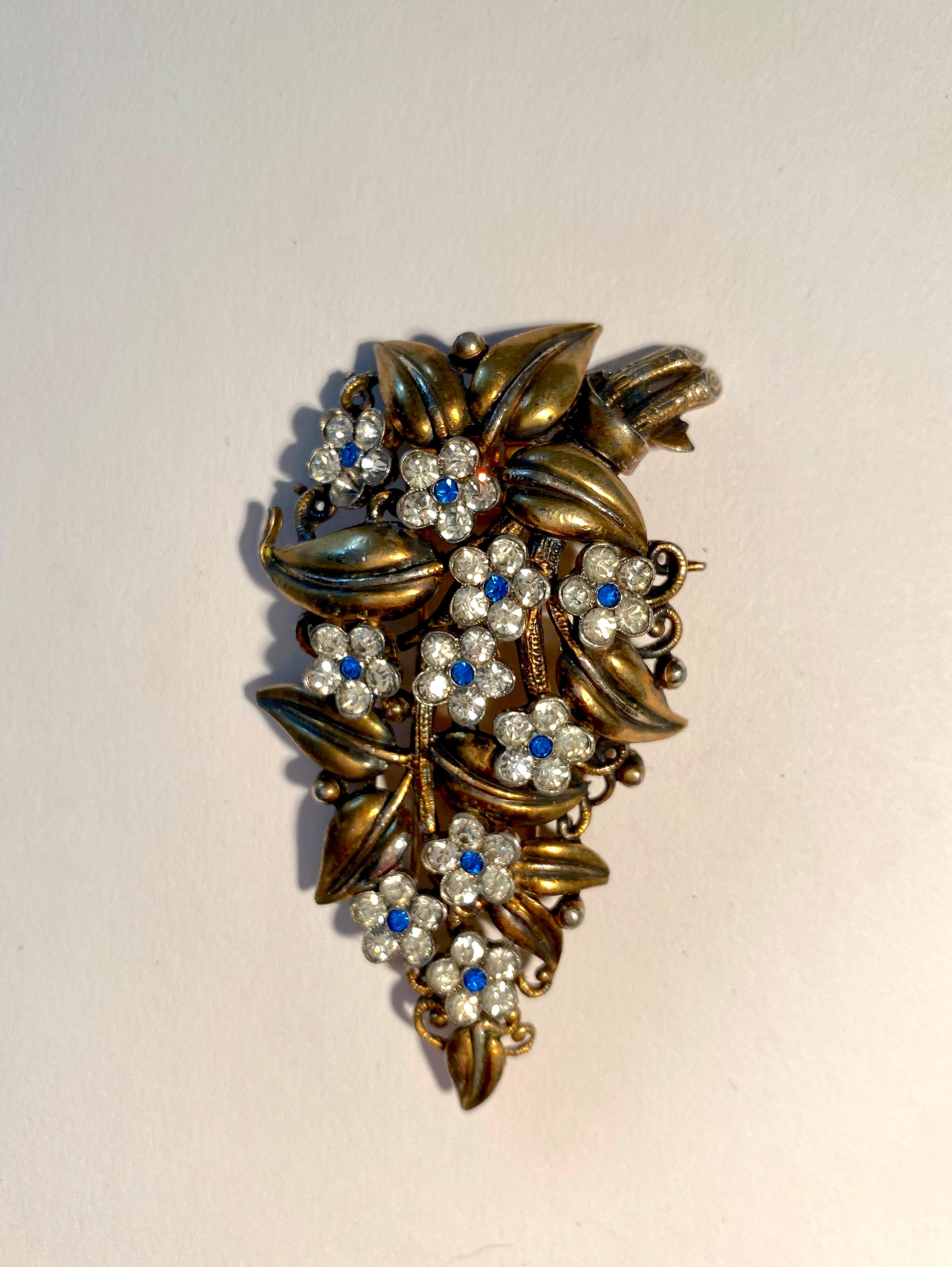 Rare 1930's Trifari Fur Clip Brooch by Alfred Philippe with lush gold leaves nestled with blue and white sparkling crystal flowers.  Produced from 1936-39, model number 115294, this spray of flowers is in good condition for it's age and is a book