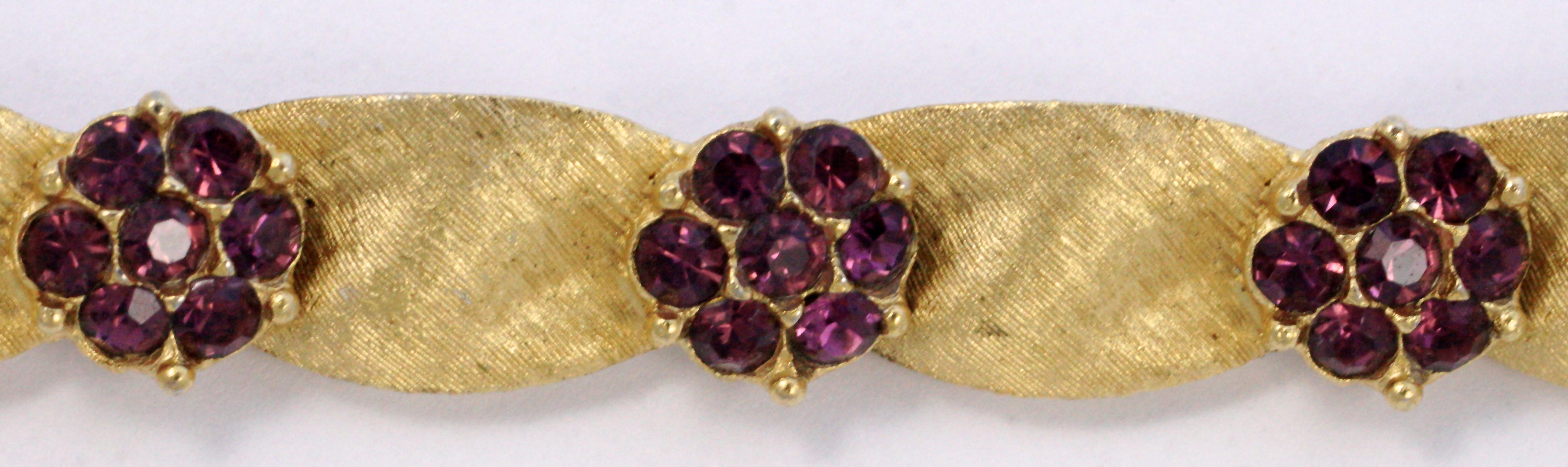 Trifari brushed gold plated ribbon design bracelet, length 18.5cm / 7.3 inches by width 9mm / .35 inch. This beautiful vintage bracelet is from Trifari's Birthday Collection, amethyst rhinestones for February. There are a few replacement stones, and