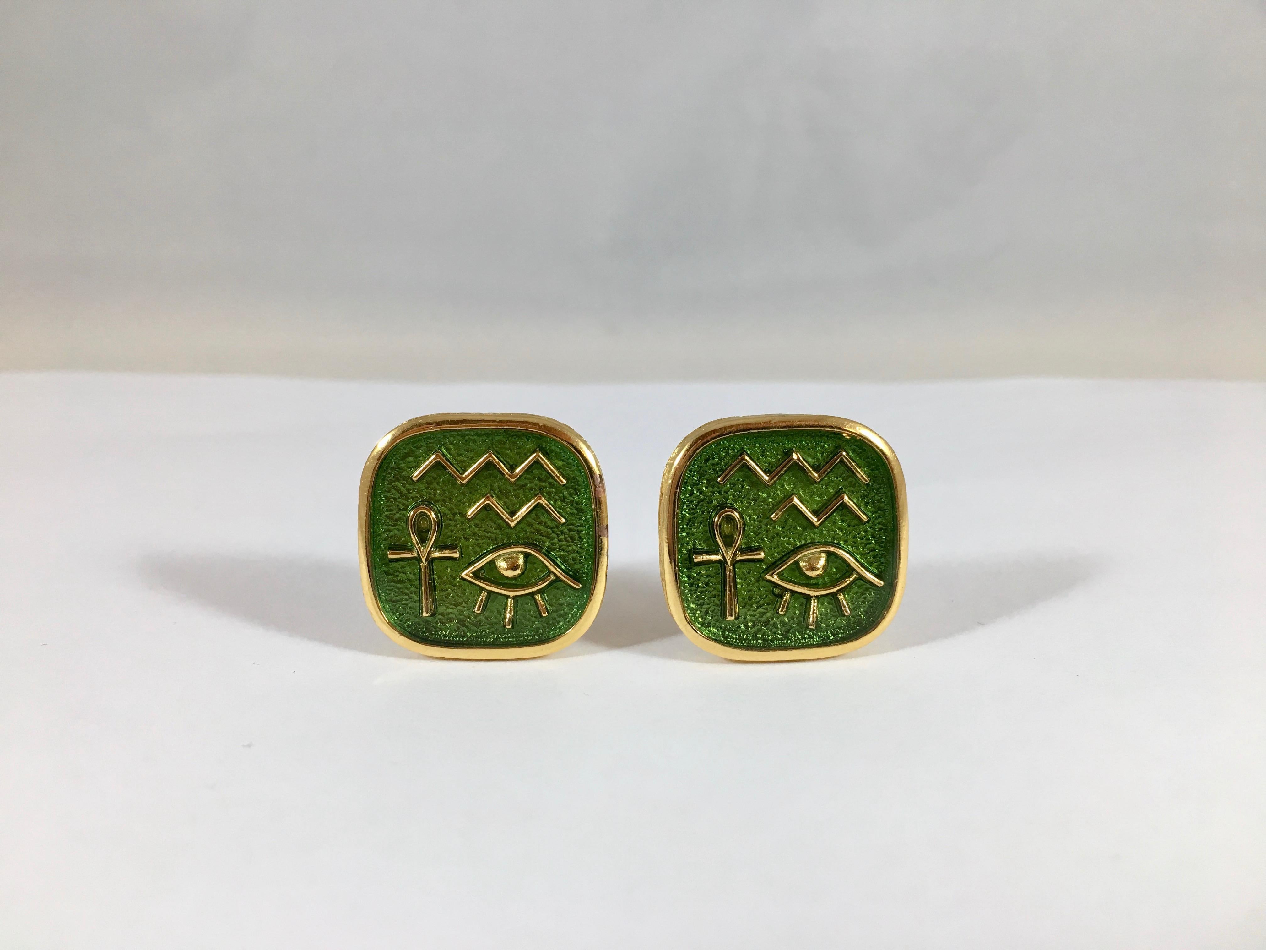 This is a an amazing pair of green 1970s Trifai Egyptian inspired clip-on earrings. They are goldtone metal with a green enamel ground that has Egyptian Hieroglyps on them. They measure 7/8 inches x 7/8 inches and are marked 'Trifari' on the back of