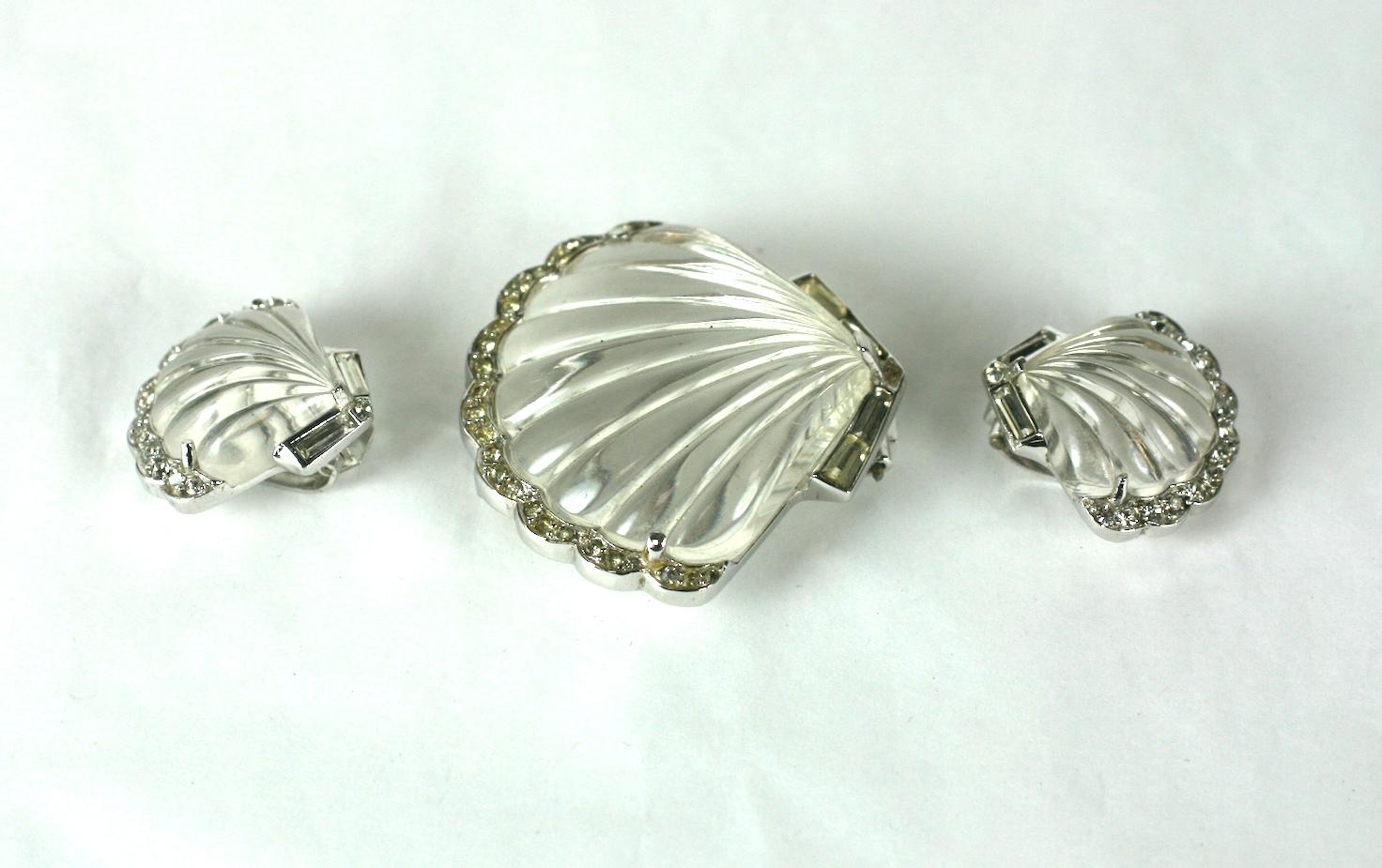 Alfred Phillipe for Trifari Moon Shell Jelly Belly demi parure consisting of a fur clip and matching ear clips. Of rhodium plated base metal, crystal rhinestones, and molded lucite scallop shells to resemble rock crystal.  
Marked Trifari with