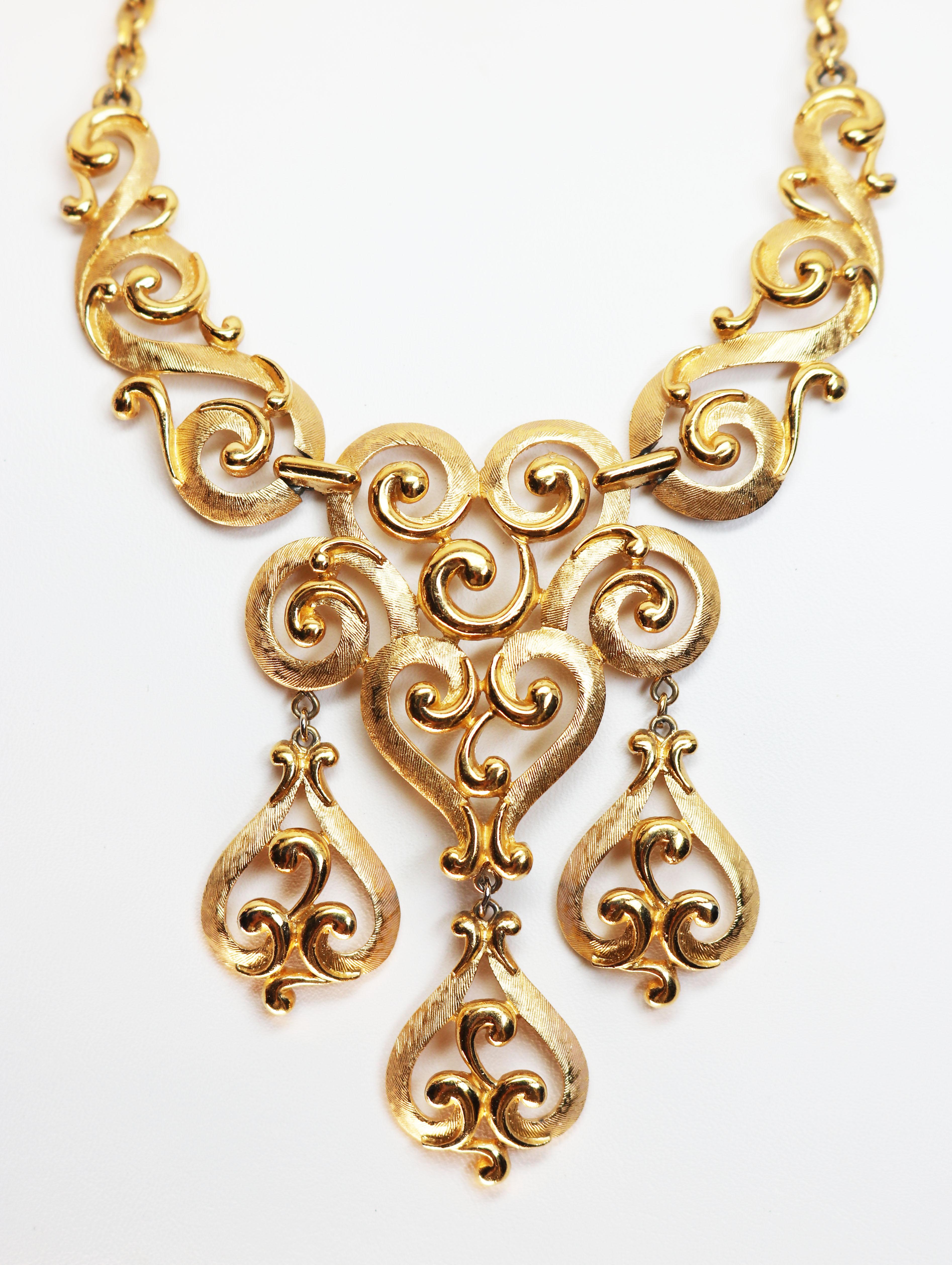 This Trifari piece has both matte and polished golden links in an elegant swirling heart shaped design. It can be adjusted to fit around your neck perfectly with the bib look which is so popular. This necklace features three articulated pendants