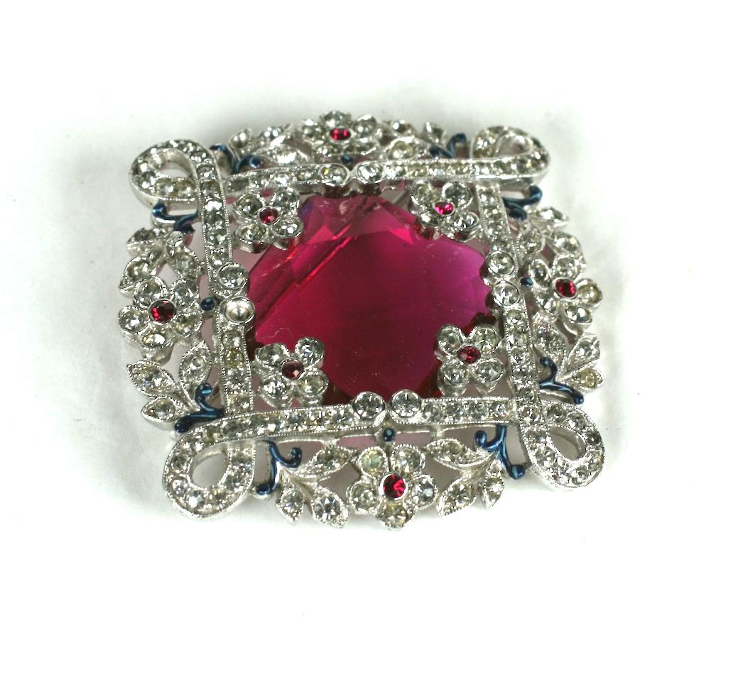  Alfred Phillipe for Trifari Ruby Art Deco Brooch with pave floral surround encasing a large shallow cut faceted stone. Pave branches are finely detailed with enamel vines and flower heads. 1930's USA.  
Alfred Phillipe for Trifari.  2.5