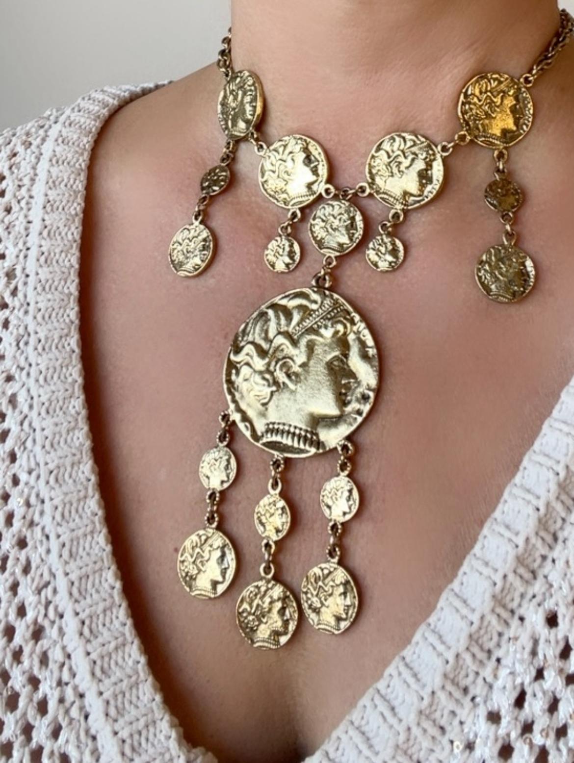 This vintage Trifari statement necklace is a bold, eye-catching masterpiece that seamlessly blends ancient Greco-Roman influences with glamorous vintage style. 

Featuring an array of intricately designed gold-toned coins, it creates a dramatic,