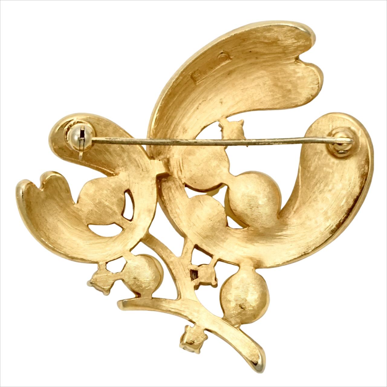 Stylish Trifari textured gold plated flower brooch, featuring cream faux pearls and clear rhinestones. Measuring 5.3 cm / 2 inches square. There is some scratching to the faux pearls.

This is a classic Trifari brooch in a wonderful floral design.