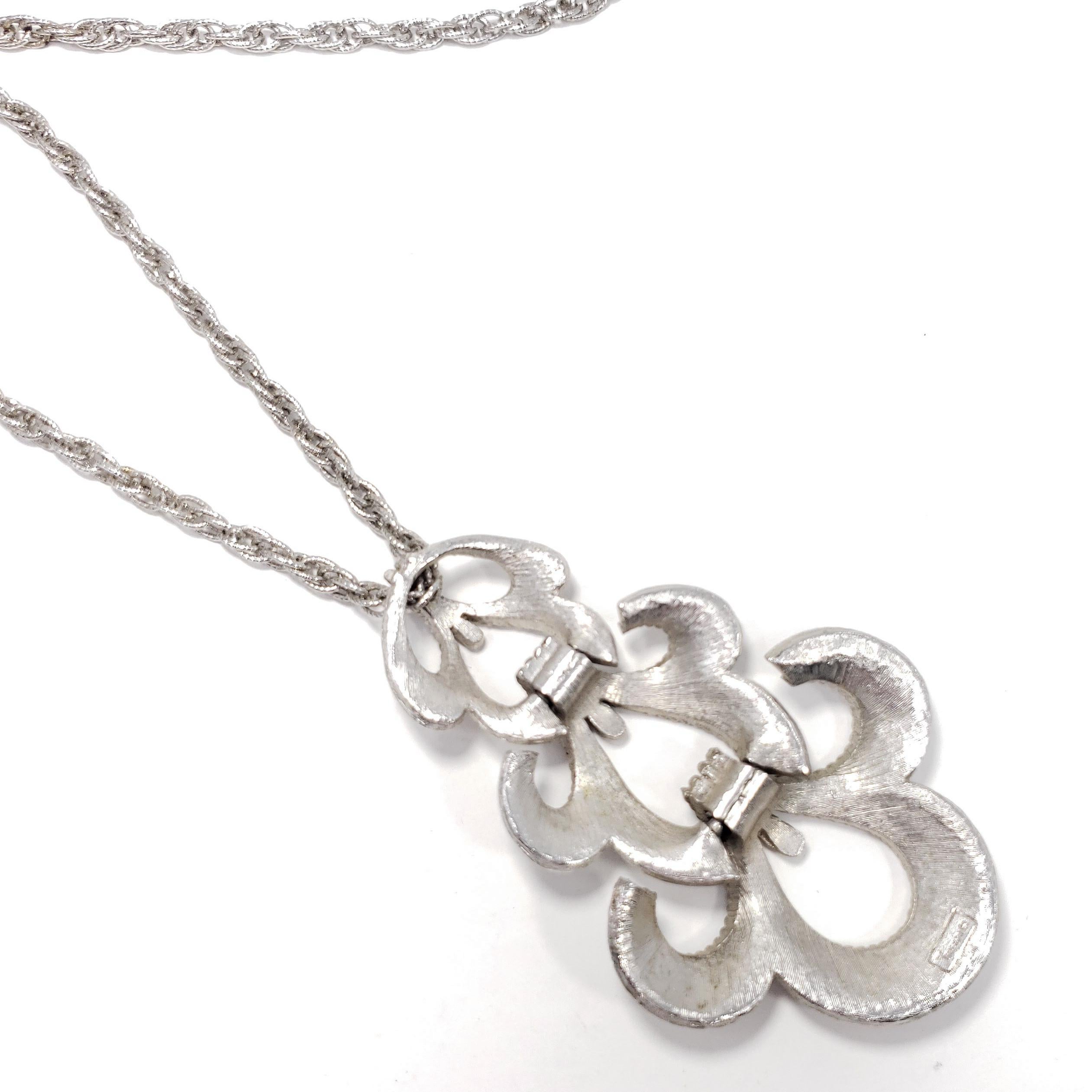 Victorian-inspired vintage silver pendant necklace by Trifari. An exquisite segmented floral-design pendant hangs off a stylish silver chain.

Silver-tone. 28 inch necklace length. Pendant 3.25 inches by 1.75 inches.

Marks / hallmarks / etc: Trifari
