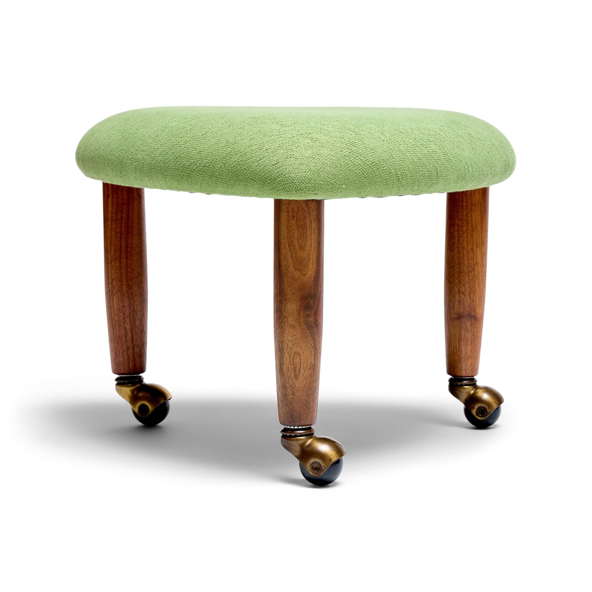 An upholstered triangular stool on a triad of solid walnut dowel legs each snugly fit with brass ball casters.