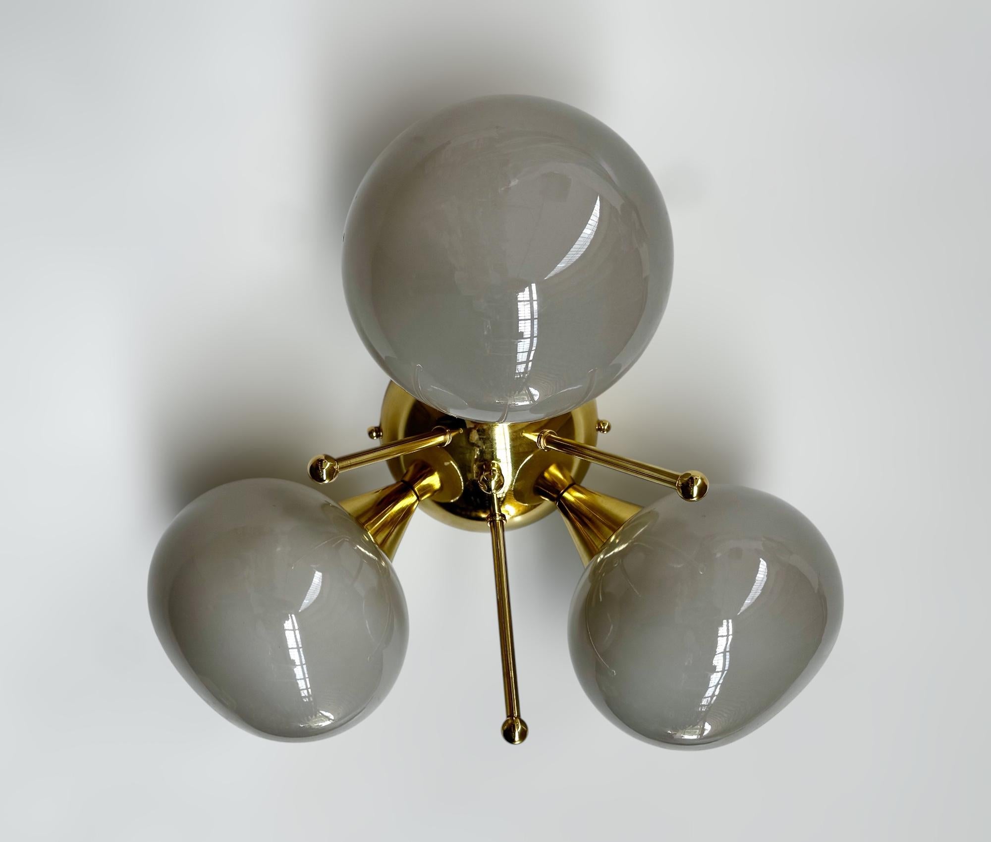 Lampada da incasso italiana con 3 paralumi in vetro di Murano a forma di ciottolo montati su una struttura in ottone massiccio con finitura in ottone laccato lucido.
Disegnato da Fabio Bergomi / Made in Italy
3 luci / tipo E12 o E14 / max 40W