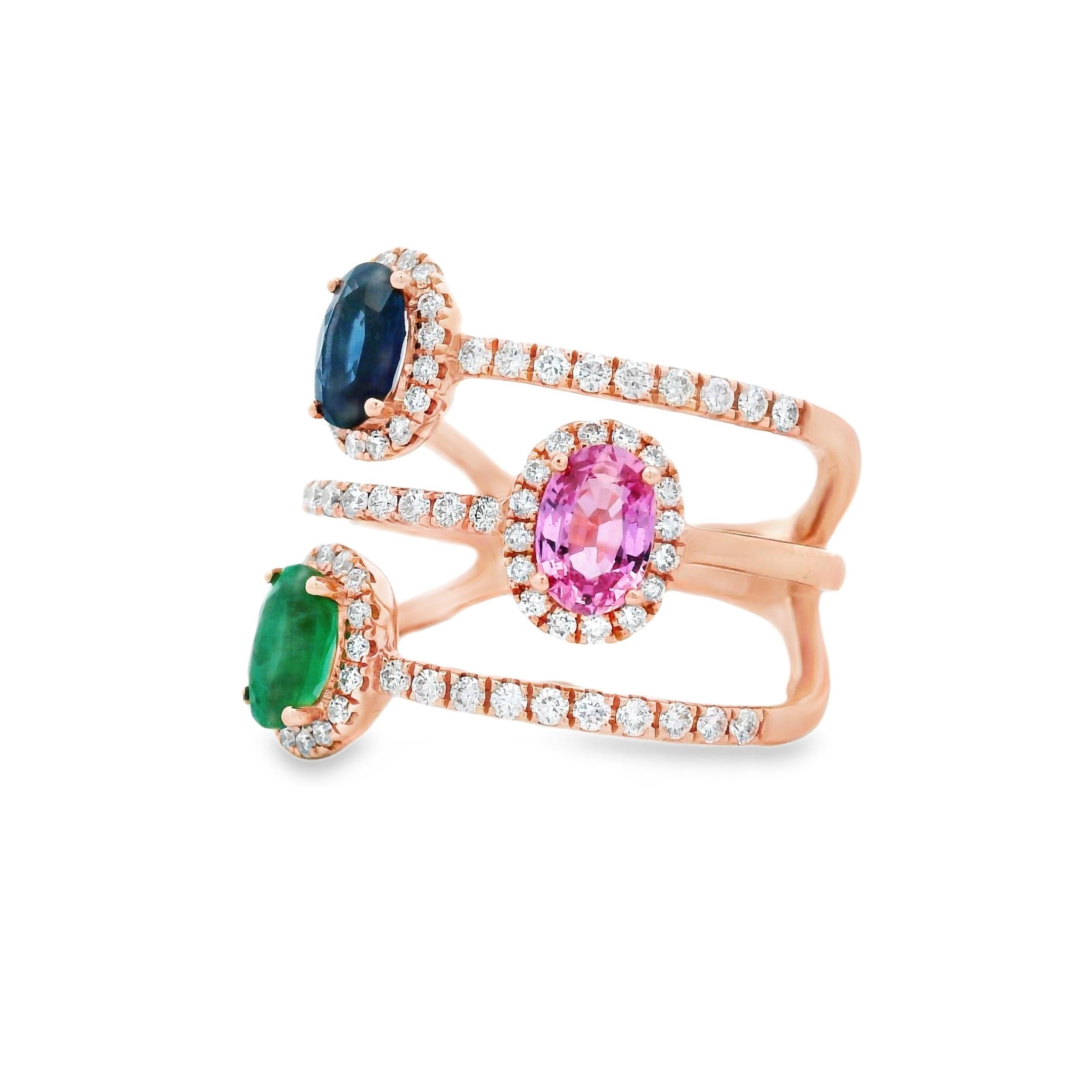 Dieser lebendige und moderne Ring im Wickelring-Stil besteht aus einem Trio reichhaltig gefärbter Edelsteine - rosa Saphir, blauer Saphir und Smaragd -, die jeweils von einem zarten Diamantenkranz umrahmt werden. Das gestaffelte Bypass-Design