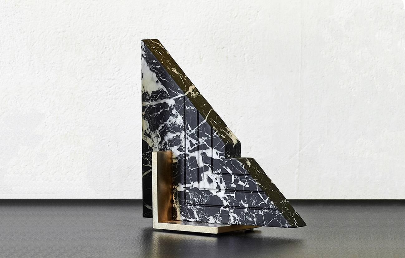 Meet Trigono; one of the new Oh So Single Odd bookend personalities.
Trigono is available in black marble and a brushed brass base.
The marble is hand carved into the geometric shape and features grooved detailing. It is sculpturally balanced over