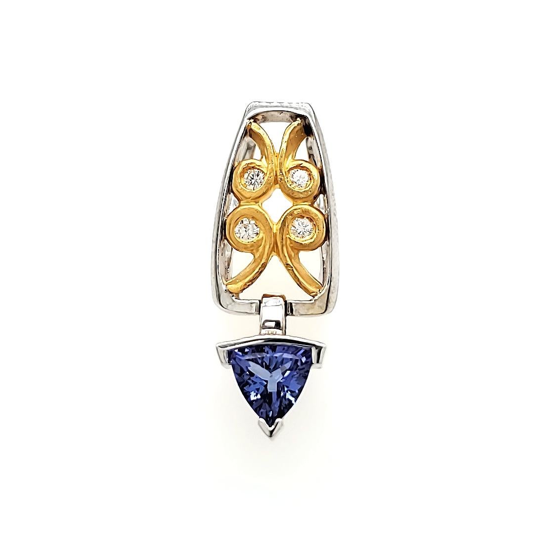 The stunning triangle-shaped Tanzanite weighing 1.05 cts takes center stage, suspended gracefully by a bale adorned with an enchanting swirly yellow gold motif. 

It is complemented by four brilliant round diamonds totaling 0.05 carats.

All set in