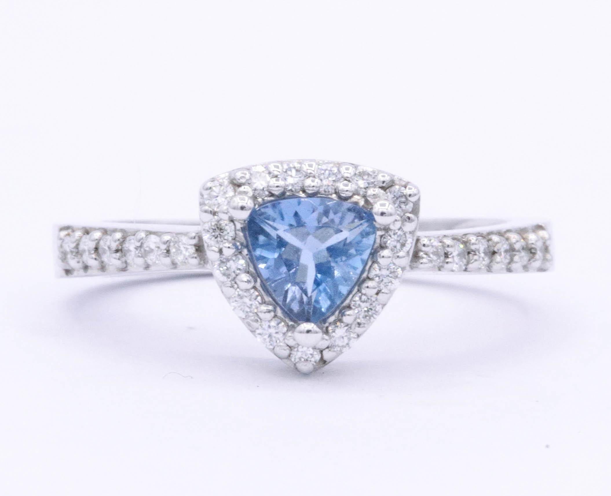 14K White gold ring featuring one trillion cut Aquamarine weighing 0.40 carats, 5 mm, flanked with round brilliants weighing 0.25 carats. Color G-H Clarity SI