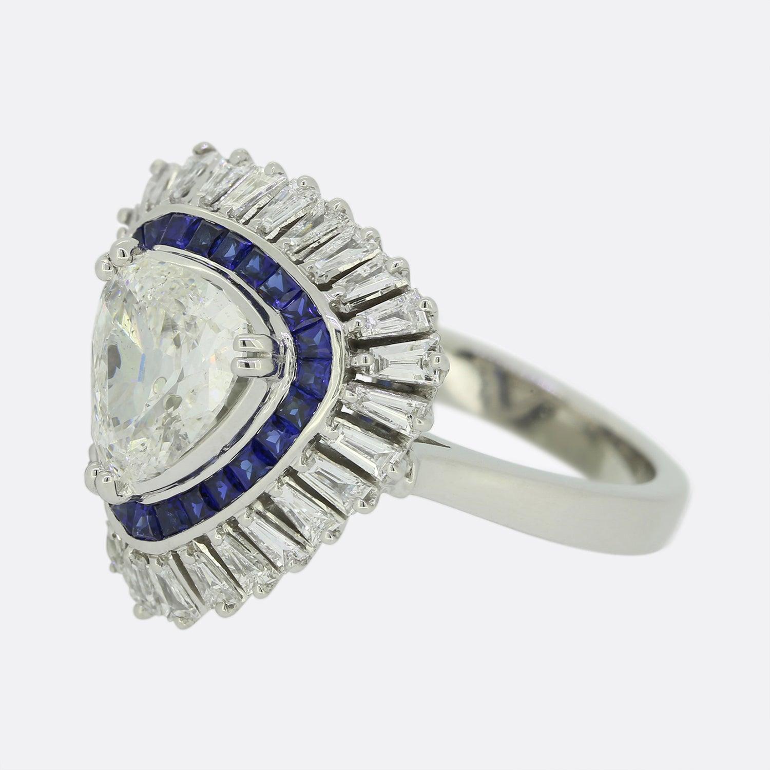 This is a wonderful modern diamond and sapphire ring. The ring plays host to a central trillion cut diamond that sits in a raised three claw mount. This is an impressive ring and although the centre stone weighs under two carats it spreads a lot