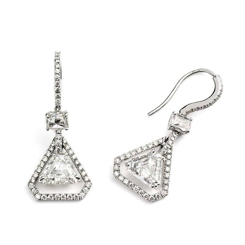 A gorgeous pair of 18k white gold diamond drop earrings. Each earring is set to the centre with a single trilliant cut diamond weighing approximately 1.05ct, colour G and VS in clarity set within a contemporary three claw setting. Complementing the
