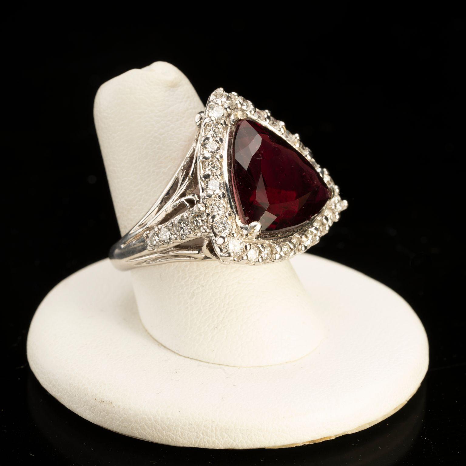 This absolutely stunning piece features a huge, dazzling, deeply-hued triangle-cut rubellite (pink tourmaline) surrounded by a plethora of brilliant white diamonds and set in an ornately detailed white gold band with accenting diamonds on the sides.