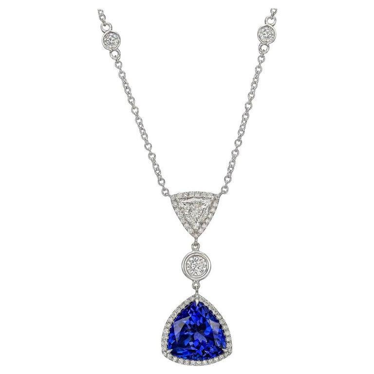 Pendant, showcasing a trillion-cut tanzanite framed by round-cut diamonds and suspended from a bezel-set round brilliant-cut diamond to a larger trillion-cut diamond framed by round-cut diamonds, set in 14k white gold.

Tanzanite weighing ~6.00