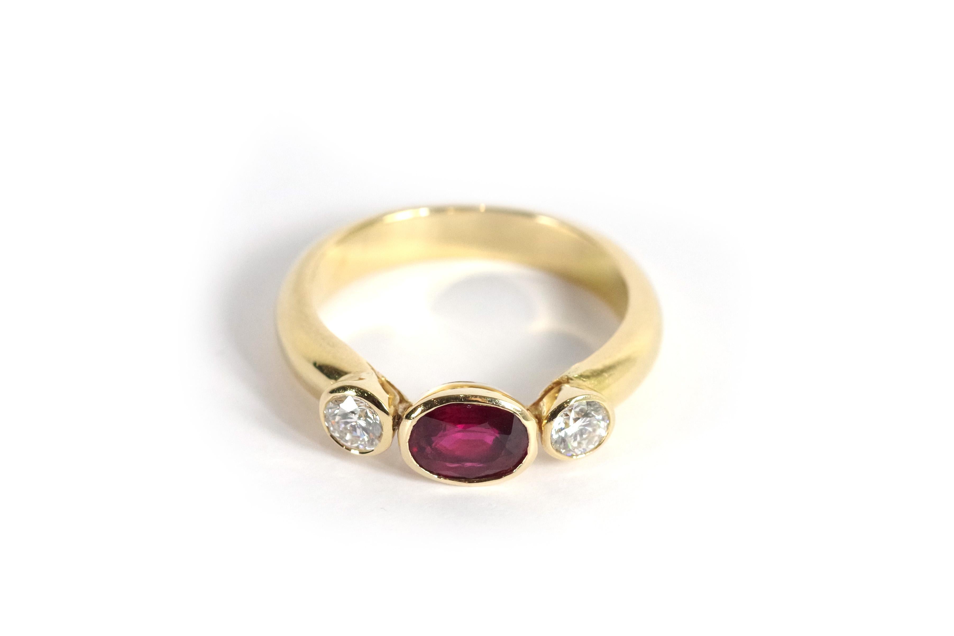 Trilogy ruby and diamond ring in 18-karat yellow gold. In the centre, a beautiful oval ruby with velvety red, weighing approximately 1.05 carats. The ruby is natural, framed by two brilliant-cut diamonds of 0.25 carats each. Vintage ring from the