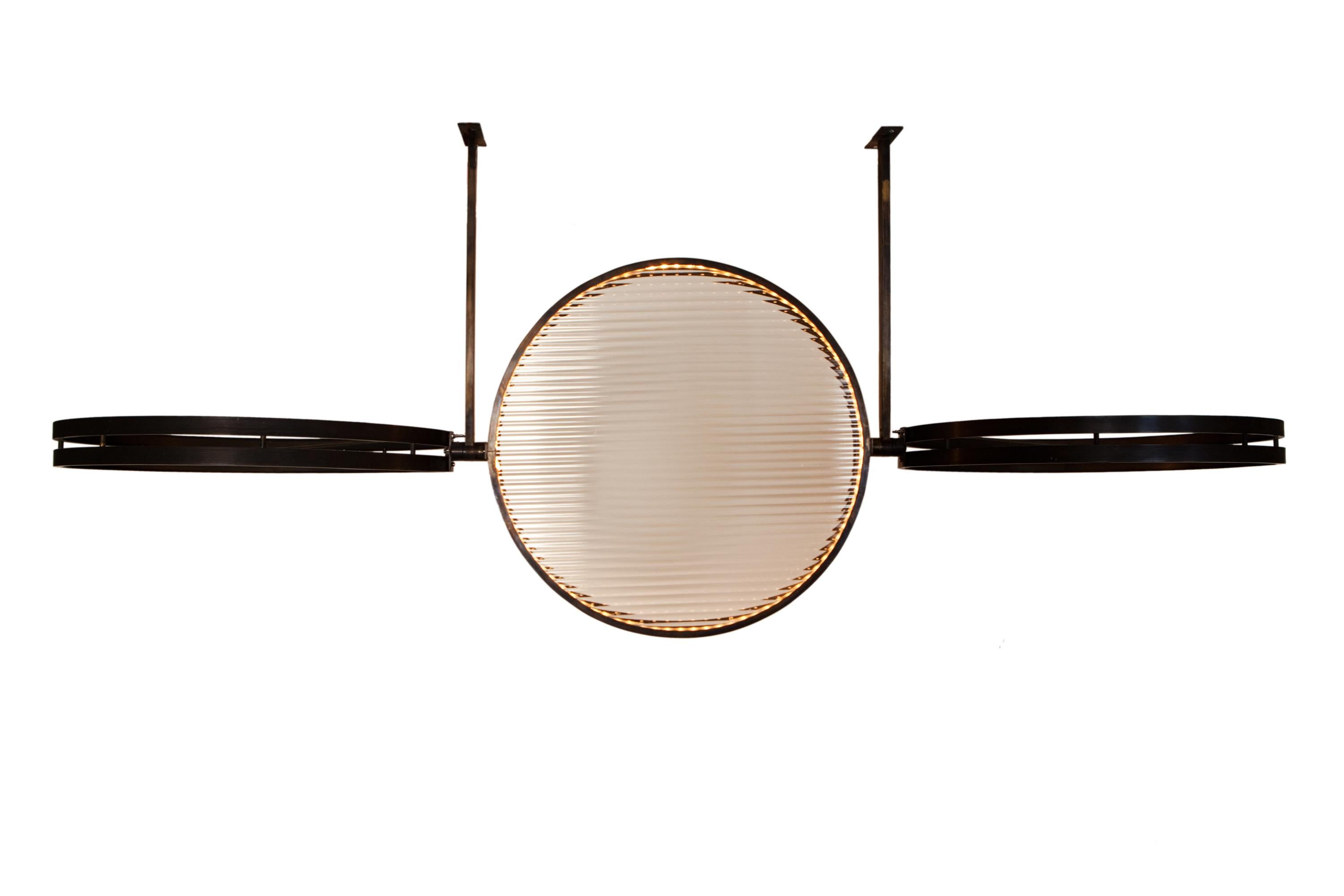 Pendant of 3 rings which are movable to each other, filled with ribbed glass, with leds. power supply placed on distance.
Bronzed brass frame. diameter of each ring is 48 cm.