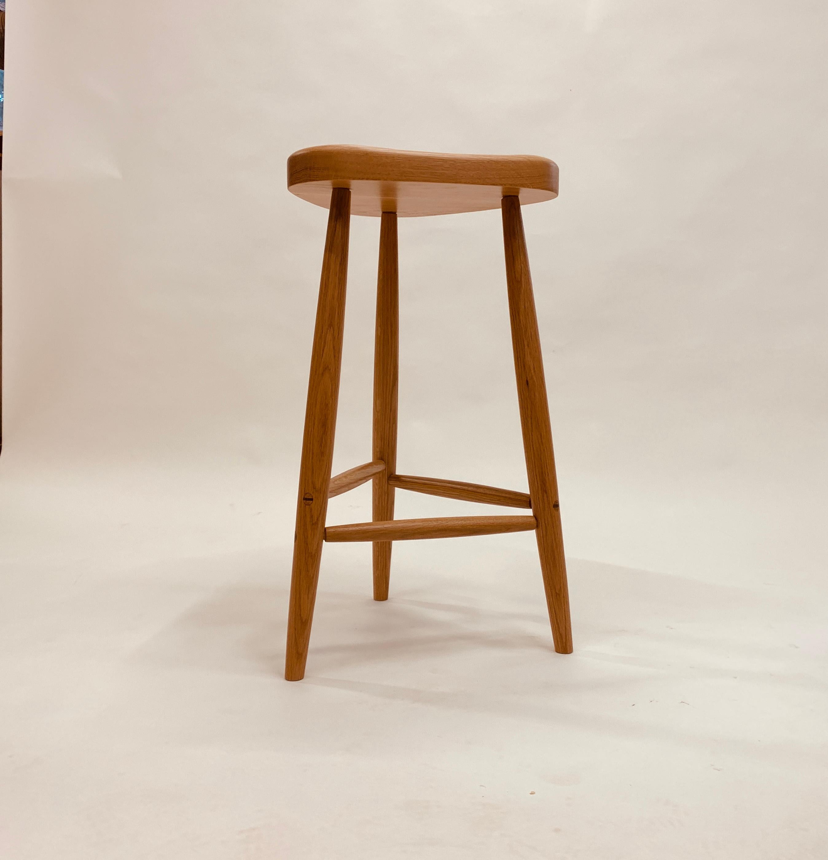 Trina es un taburete clásico para la encimera de tu cocina.  Está disponible en roble o cerezo y mide 27 pulgadas de alto.  Los espárragos pasantes se fijan con cuñas.  El asiento contorneado ofrece comodidad en varias orientaciones, mientras que