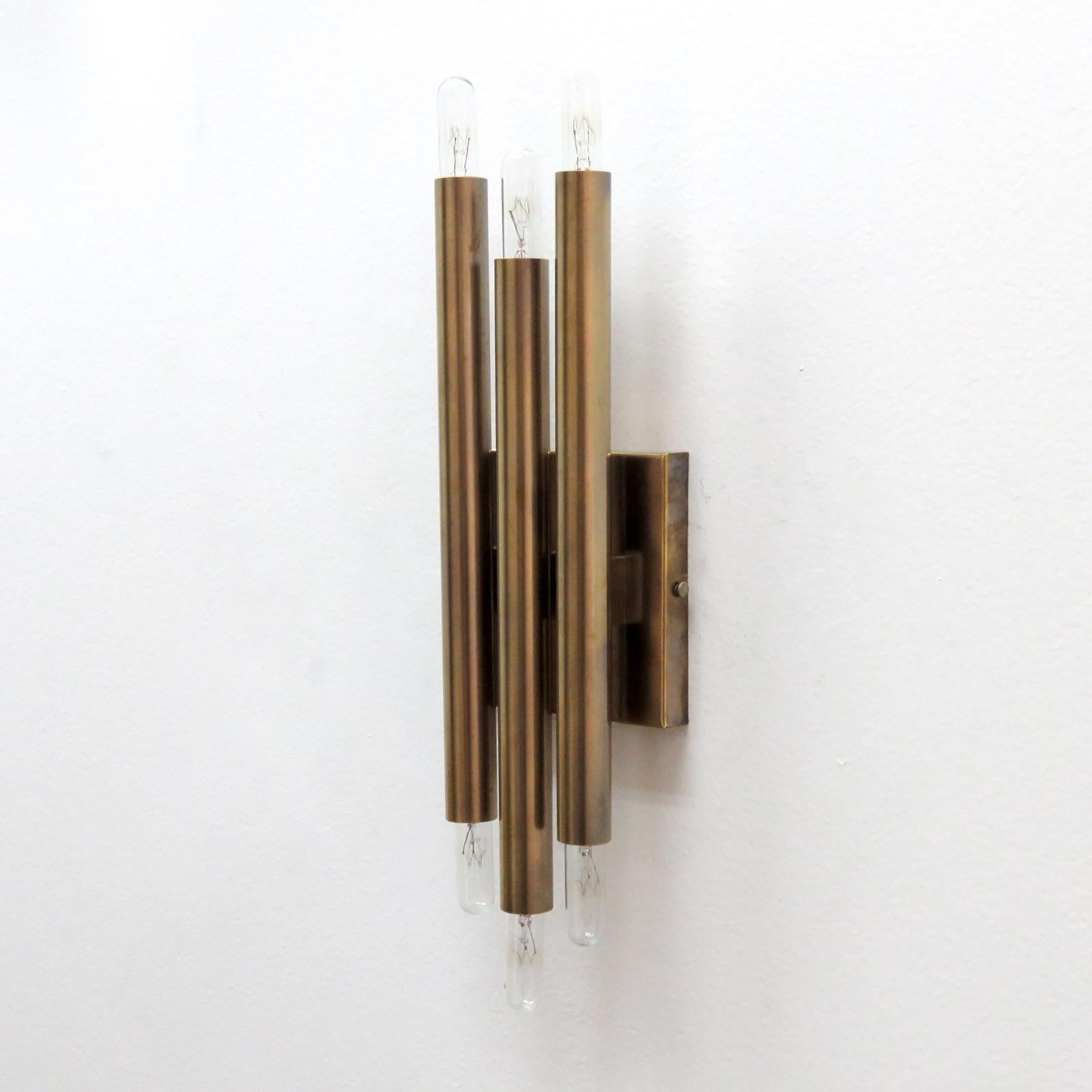 Magnifique applique géométrique en laiton brut vieilli de Gallery L7, fabriquée et finie à la main à Los Angeles en laiton américain, avec trois bougies doubles verticales. Six douilles candélabres E12 par luminaire, puissance maximale de 40 W